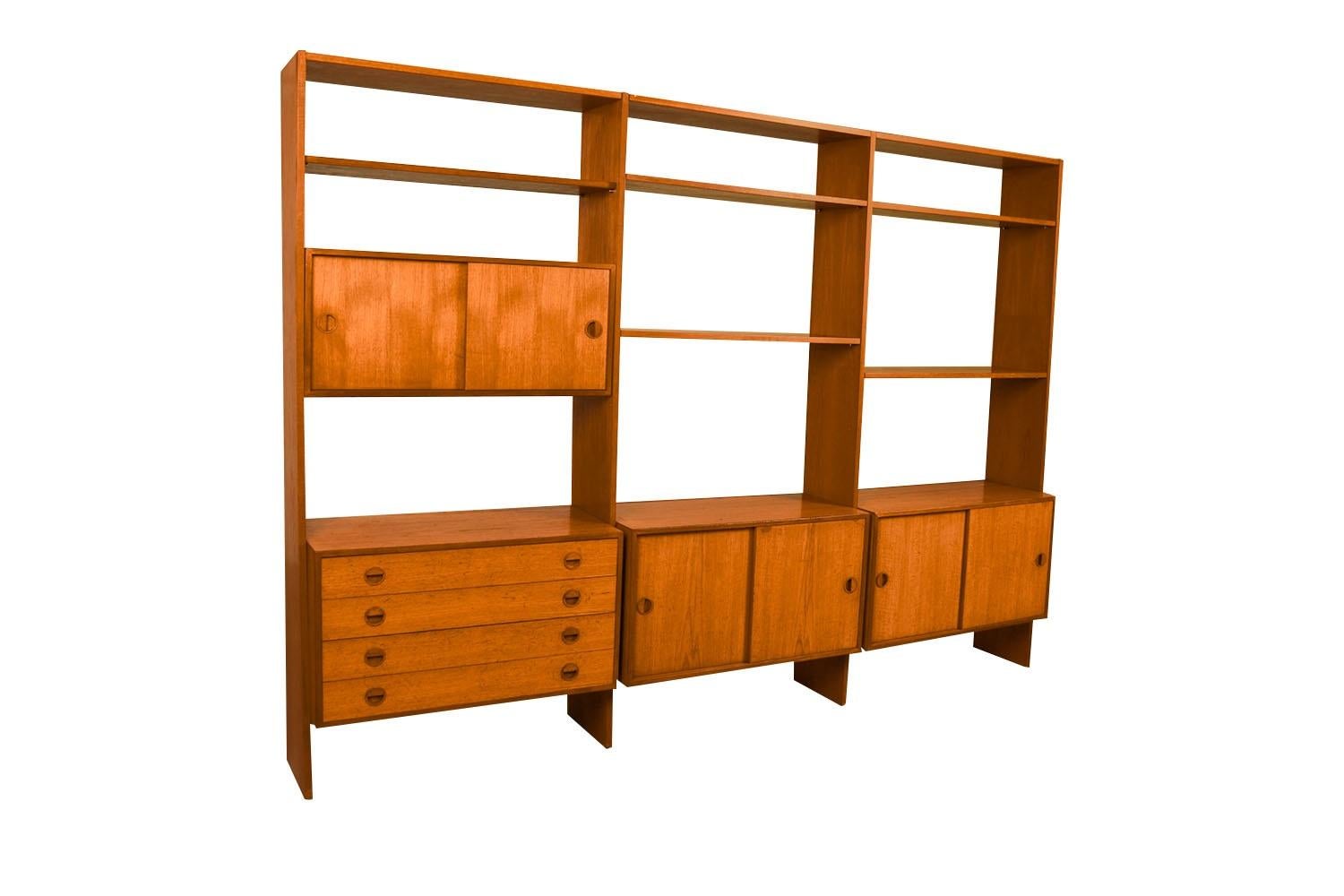A remarkable teak, freestanding, modular, room divider, three bay bookcase, cabinet, made in Denmark by Hansen & Guldborg features gorgeous teak tones and grain. Right side offers two open-adjustable shelf areas with a lower double door cabinet