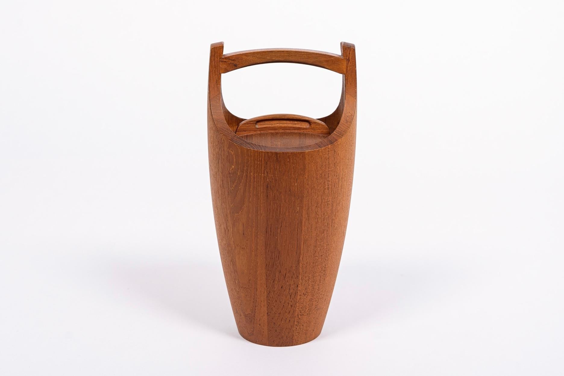 This vintage mid-century Danish modern large teak ice bucket was designed by Jens H. Quistgaard for Dansk circa 1950. This iconic piece features classic Scandinavian modern design with simple, clean lines and gentle, elegant curves. The ice bucket