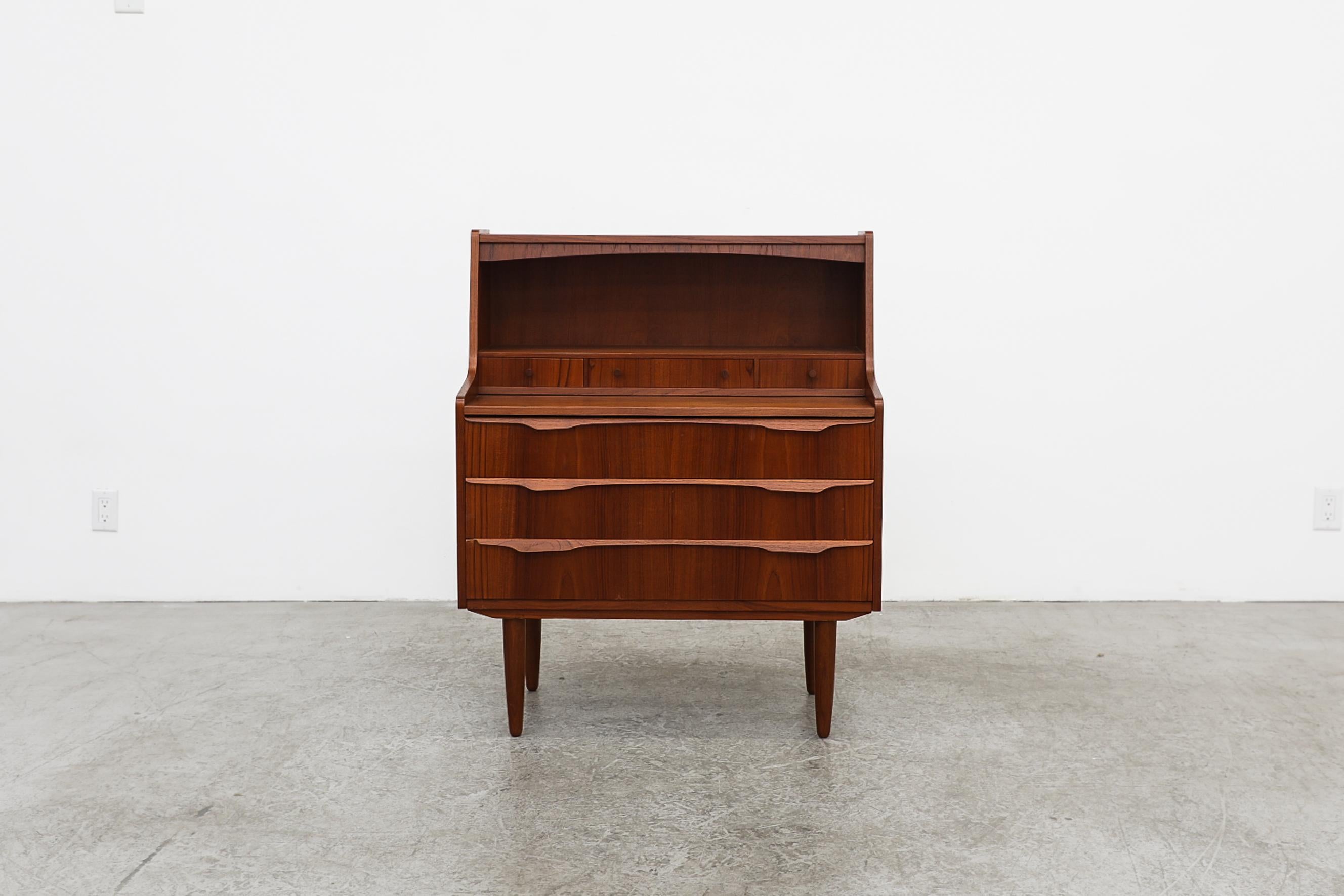 Little Mid-Century Danish teak vanity, desk or dresser with tapered legs. Lightly refinished with pull-out desk and little drawers and compartments on top with lower stacked dresser drawers. In good overall original condition with wear and