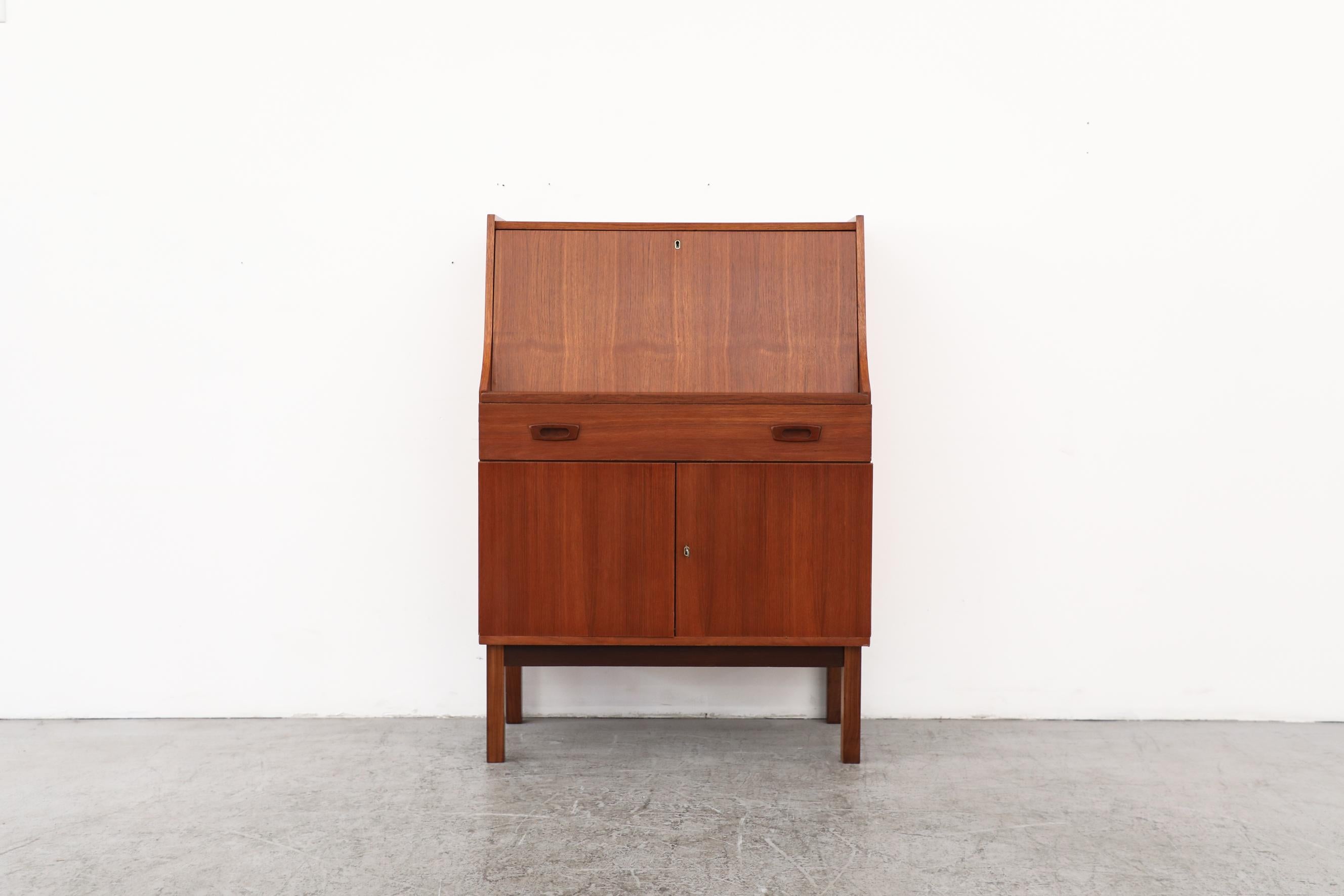 Mid-century Danish teak secretary desk or vanity with organizer cubbies and shelf inside, a long drawer over a lower locking cabinet. In original condition with visible wear consistent with its age and use. Top lock does not function.