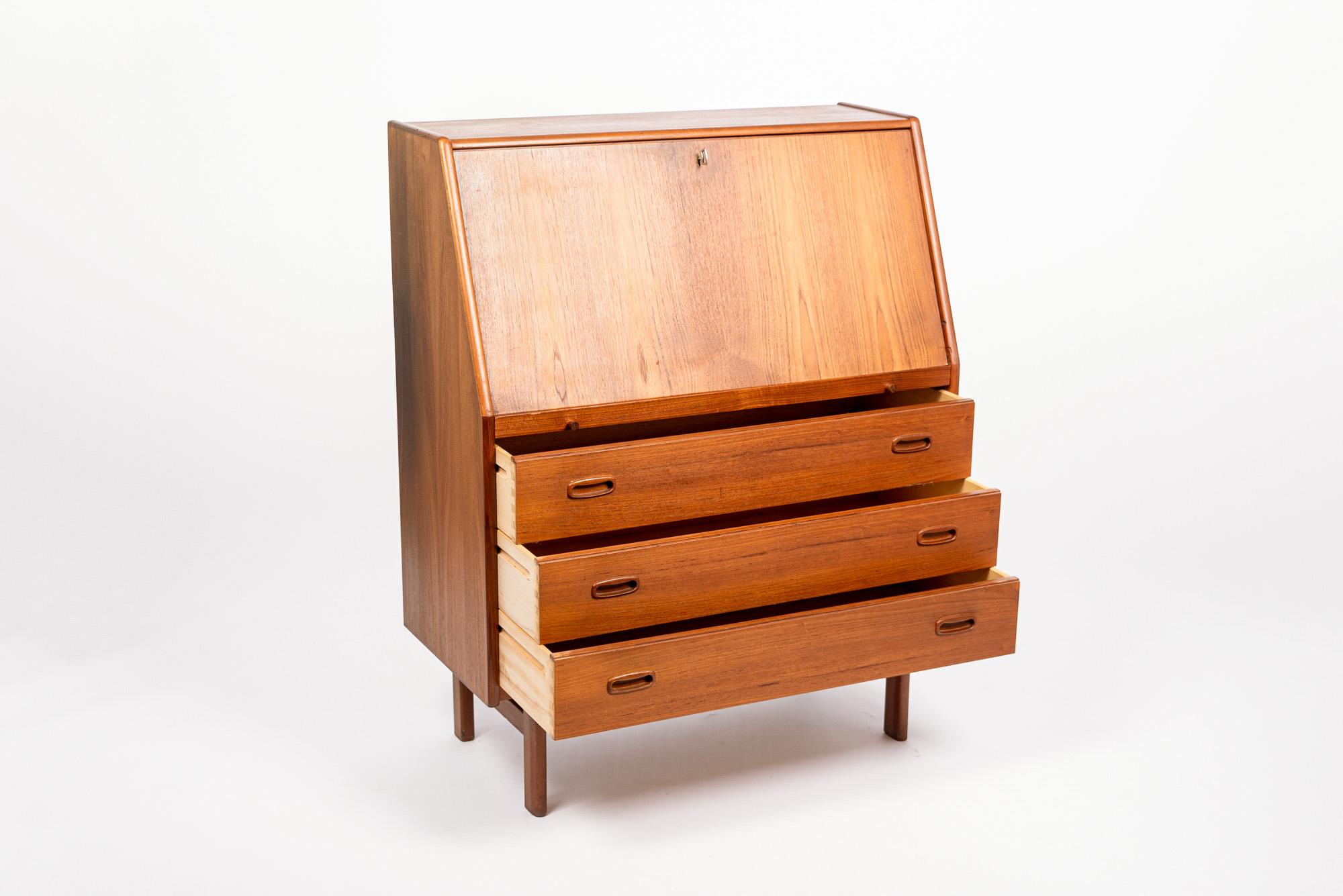This mid century Danish modern teak wood secretary desk by Bernhard Petersen & Son for BPS Mobler was made in Denmark circa 1960. The classic Scandinavian modern design has clean, minimalist lines and gentle curves and is well-crafted from teak