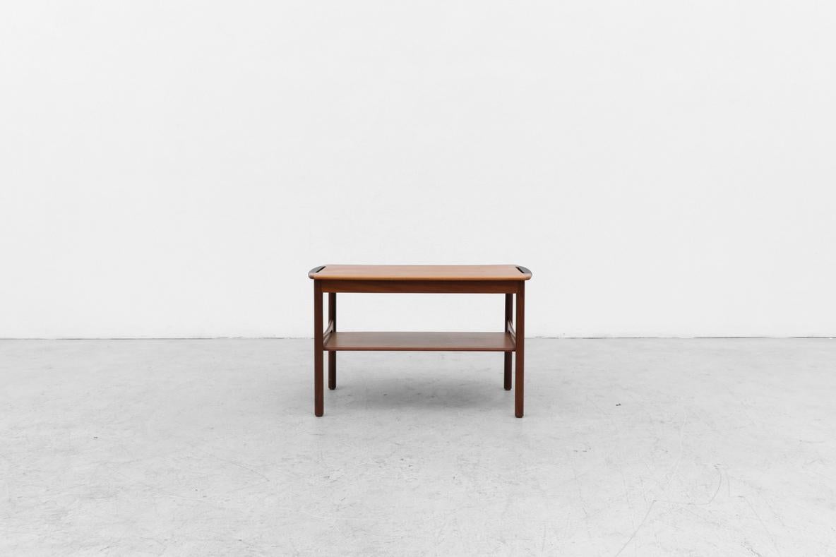 Table de service ou d'appoint en teck du milieu du siècle, inspirée par Johannes Andersen, avec plateau et poignées enveloppées de gomme. Il y a une étagère inférieure pour un rangement supplémentaire. En bon état, légèrement rénové, avec une