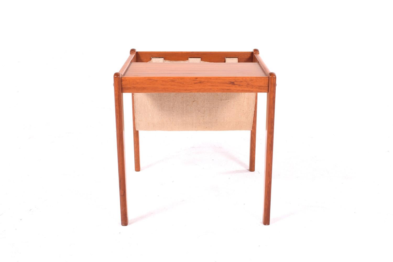 Danish teak side table with fabric magazine holder by Furbo. The item has been refinished and is in very good condition.