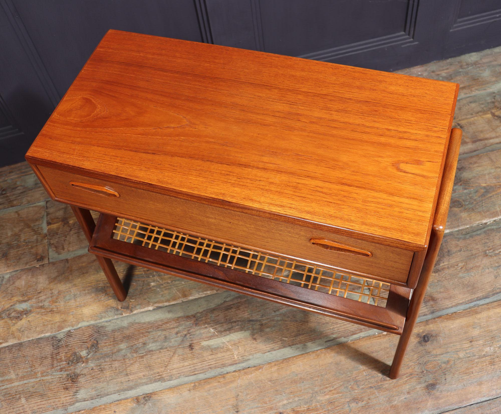 A Mid century Danish Modern entrance console / side table in teak, one long drawer with two inset sculpted handles and slanted lower shelf with woven split cane, in excellent vintage condition with minor restorations, small break in cane-work.
Age: