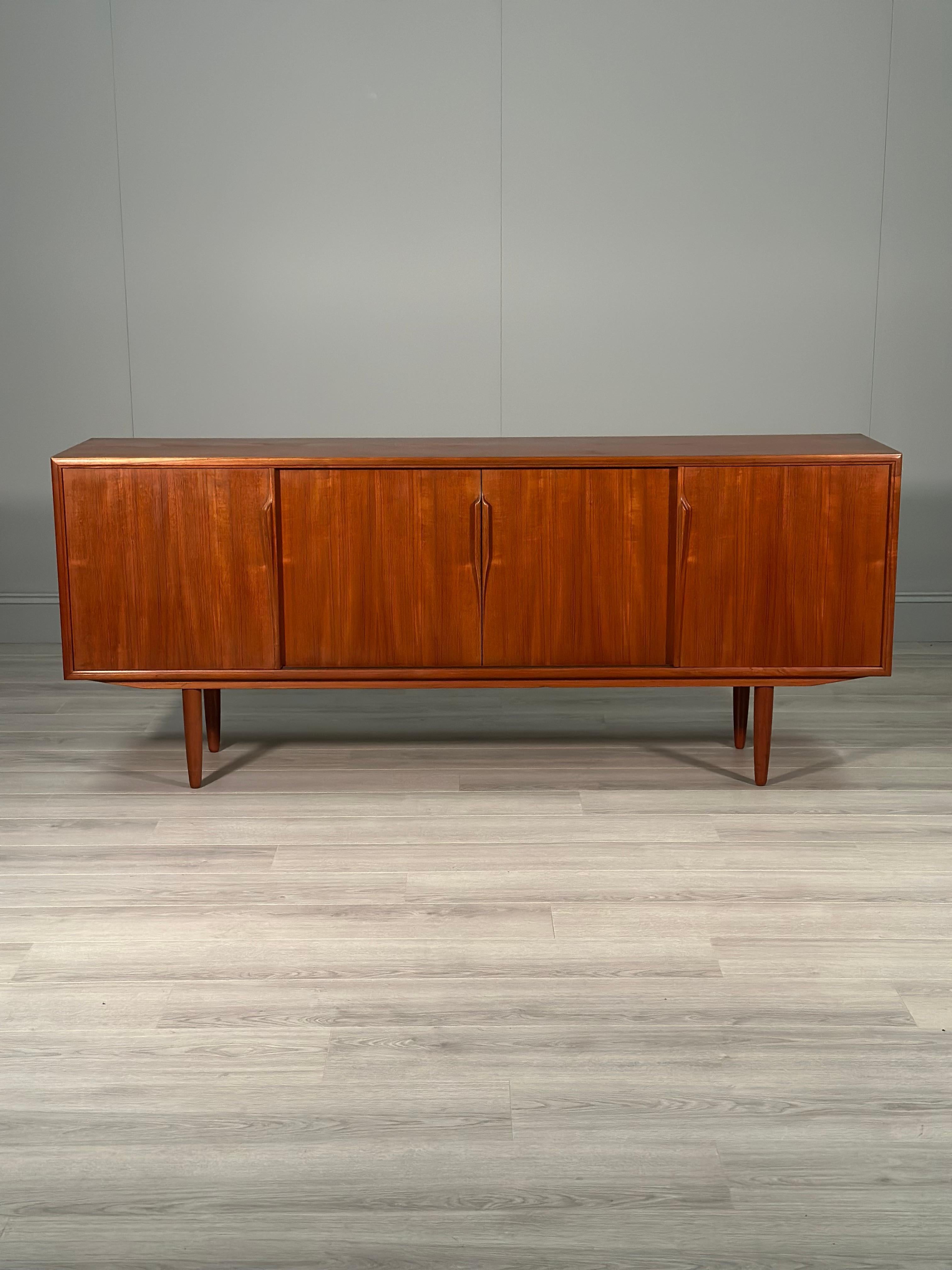 This sideboard is designed by Axel Christensen and manufactured by ACO Møbler Denmark in the 1960s. The sideboard consits of 4 sliding doors with 2 side cupboards one being larger than the other and a centre space with 3 pull out drawers. The