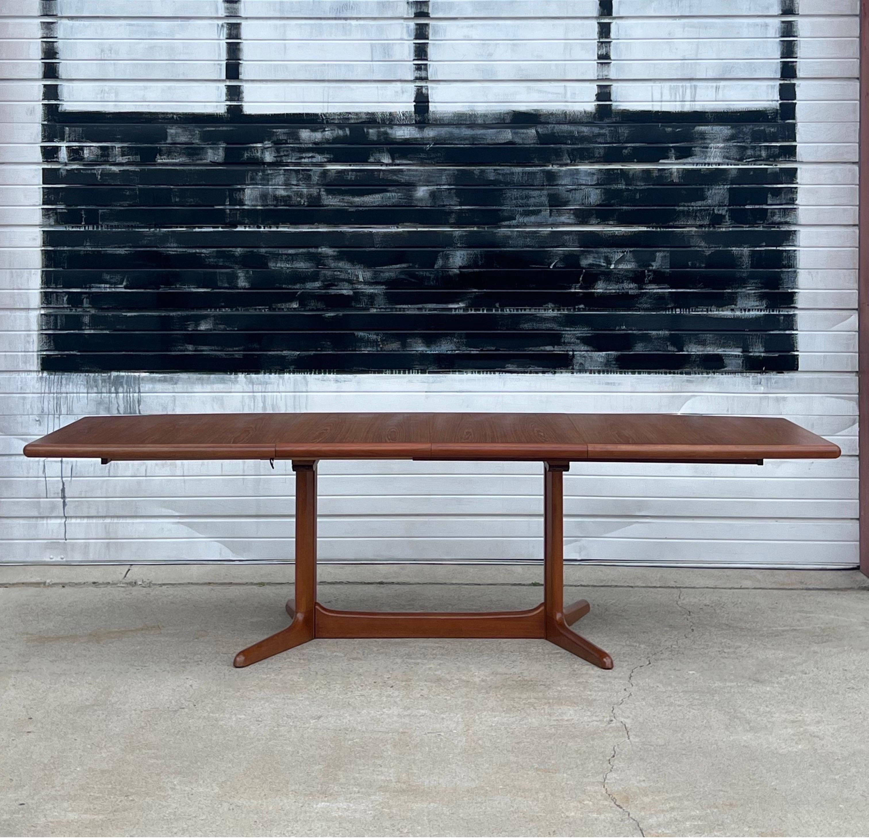 A fantastic mid-century Danish teak dining table with two leaves by Skovby, Denmark circa 1970s.. Two leaves with hidden under table storage. No need to store leaves in a closet or attic. Beautiful teak grain throughout the tabletop and legs.