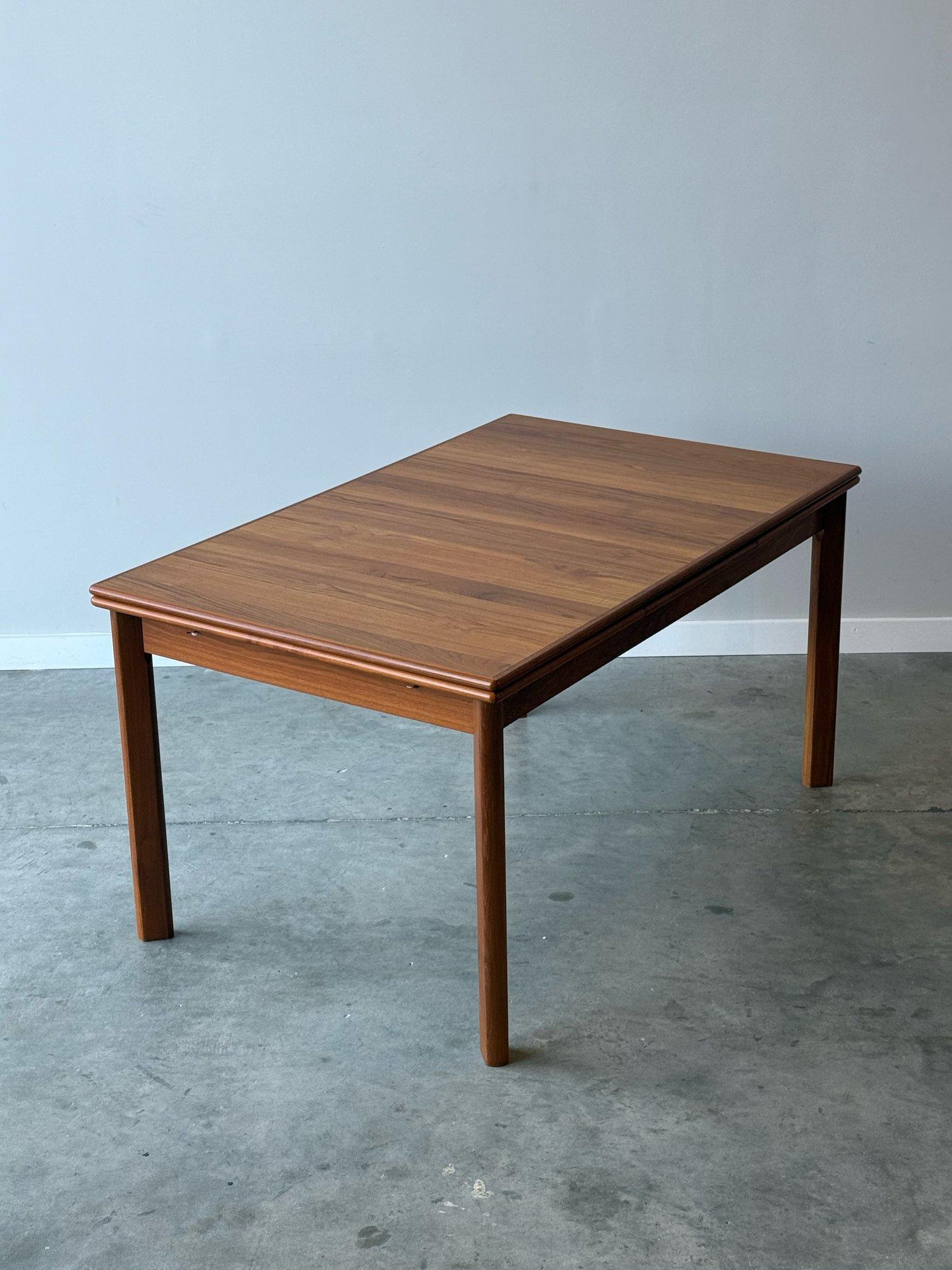 Table de salle à manger danoise en teck du milieu du siècle. De forme rectangulaire avec deux feuilles extensibles. Les feuilles se glissent sous le plateau de la table principale pour faciliter le rangement et l'accès. Magnifique grain de teck