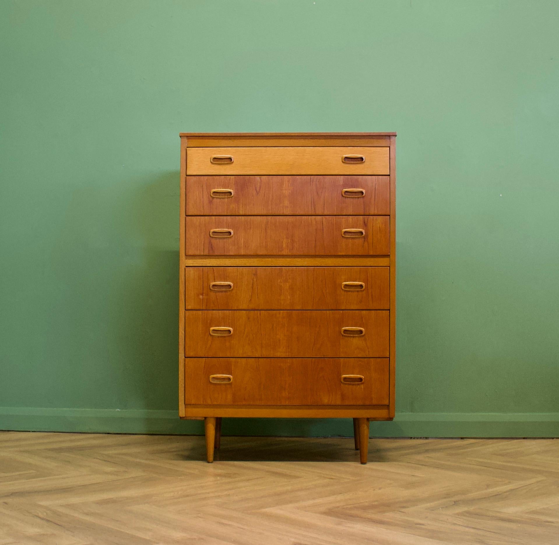 A mid century Danish teak tallboy chest of drawers - circa 1960s


Featuring 6 drawers and solid teak handles and legs
Standing on slightly splayed legs