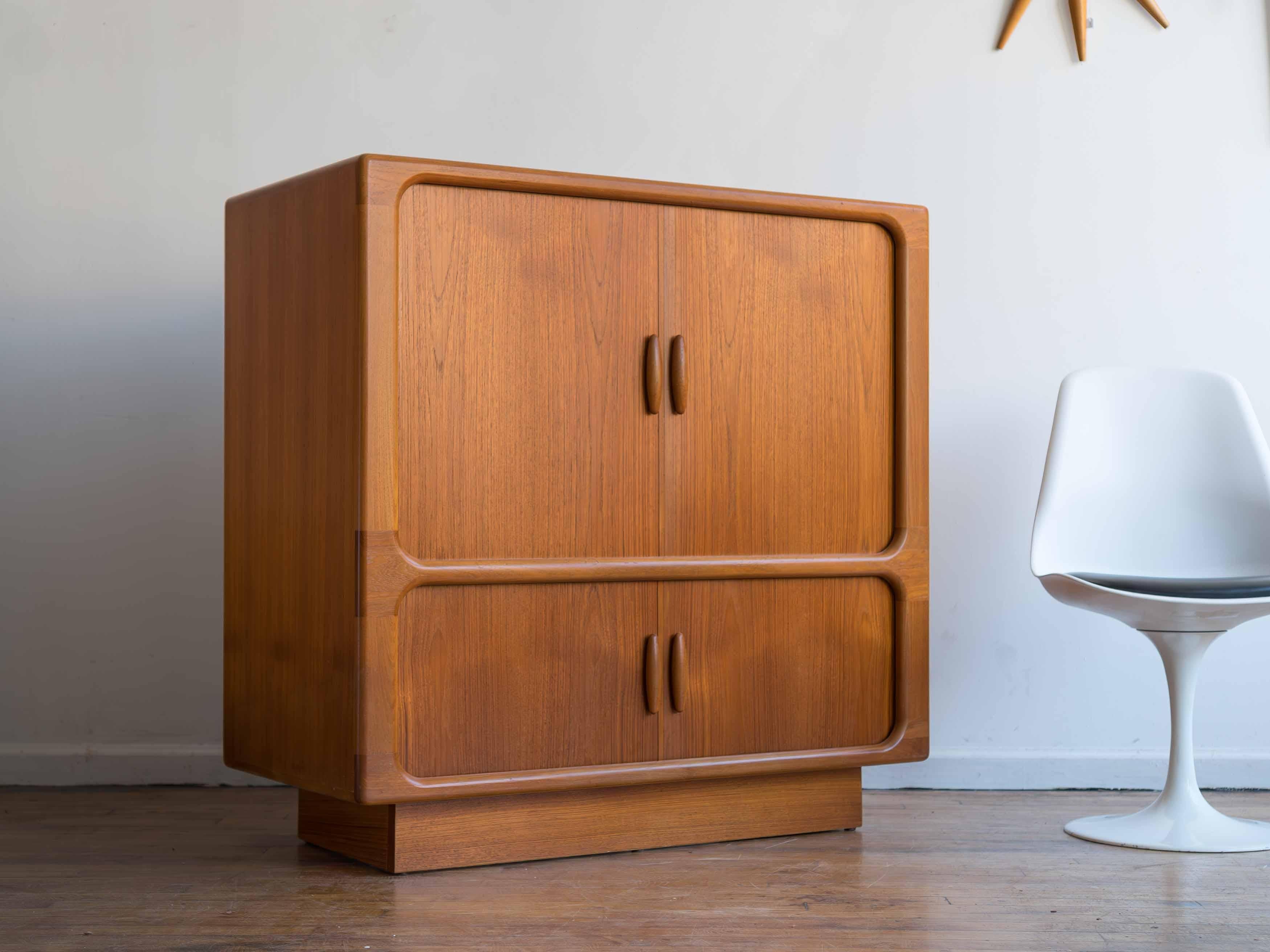 41.5” x 21.5” x 41.5”H; top compartment 33” X 21.5”H

Danish teak tambour door media cabinet made by Dyrlund circa 1970s. 
•upper and lower tambour doors with rounded, sculpted pulls
•the bottom compartment features a pull-out tray for electronics