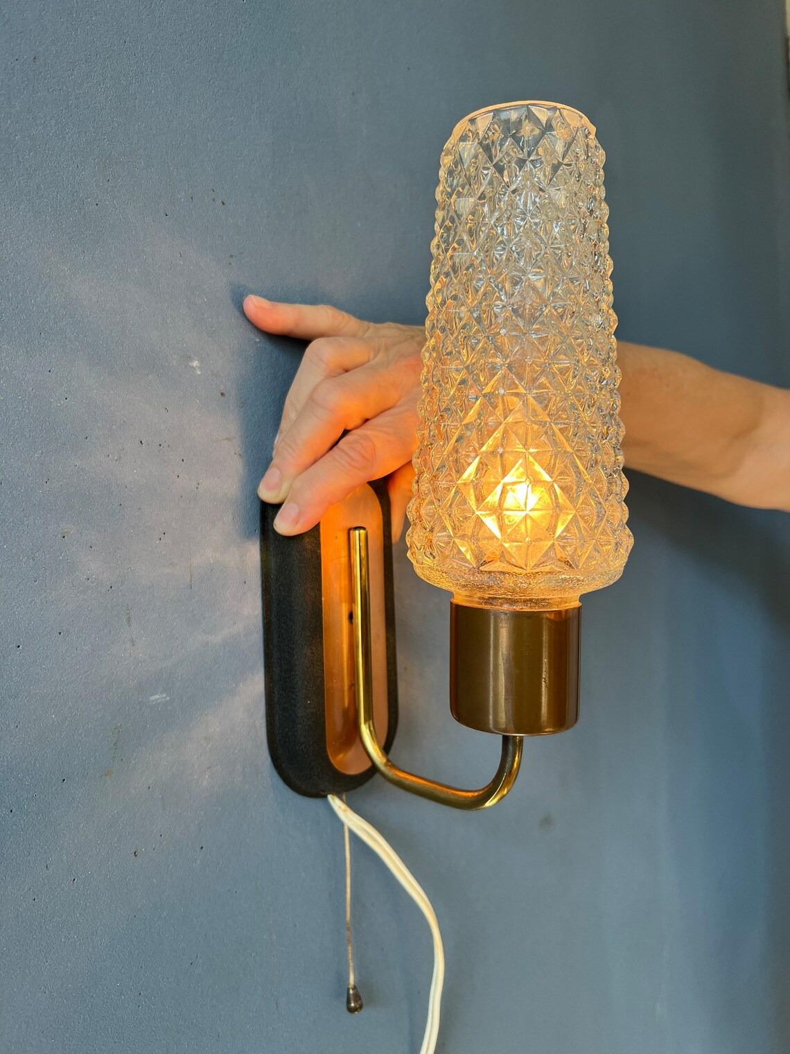 Mid century Danish wall light with glass shade. The lamp is made out metal, glass and wood. The lamp requires one E27 lightbulb and currently has an EU-plug.

Additional information:
Materials: Metal, plastic
Period: 1970s
Dimensions:ø: 7 cm
Height: