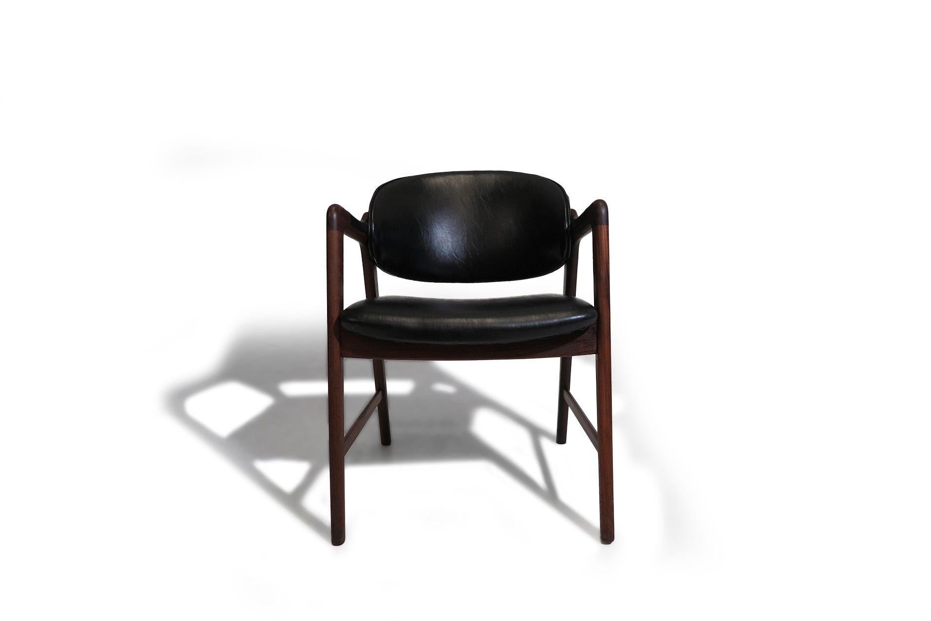Pareja de sillones de salón de nogal de mediados de siglo, atribuidos a Hovmand-Olsen, con armazón de nogal esculpido y cómodo respaldo curvado; tapizados con la tapicería original de vinilo negro. Buen estado, con ligeros signos de antigüedad y