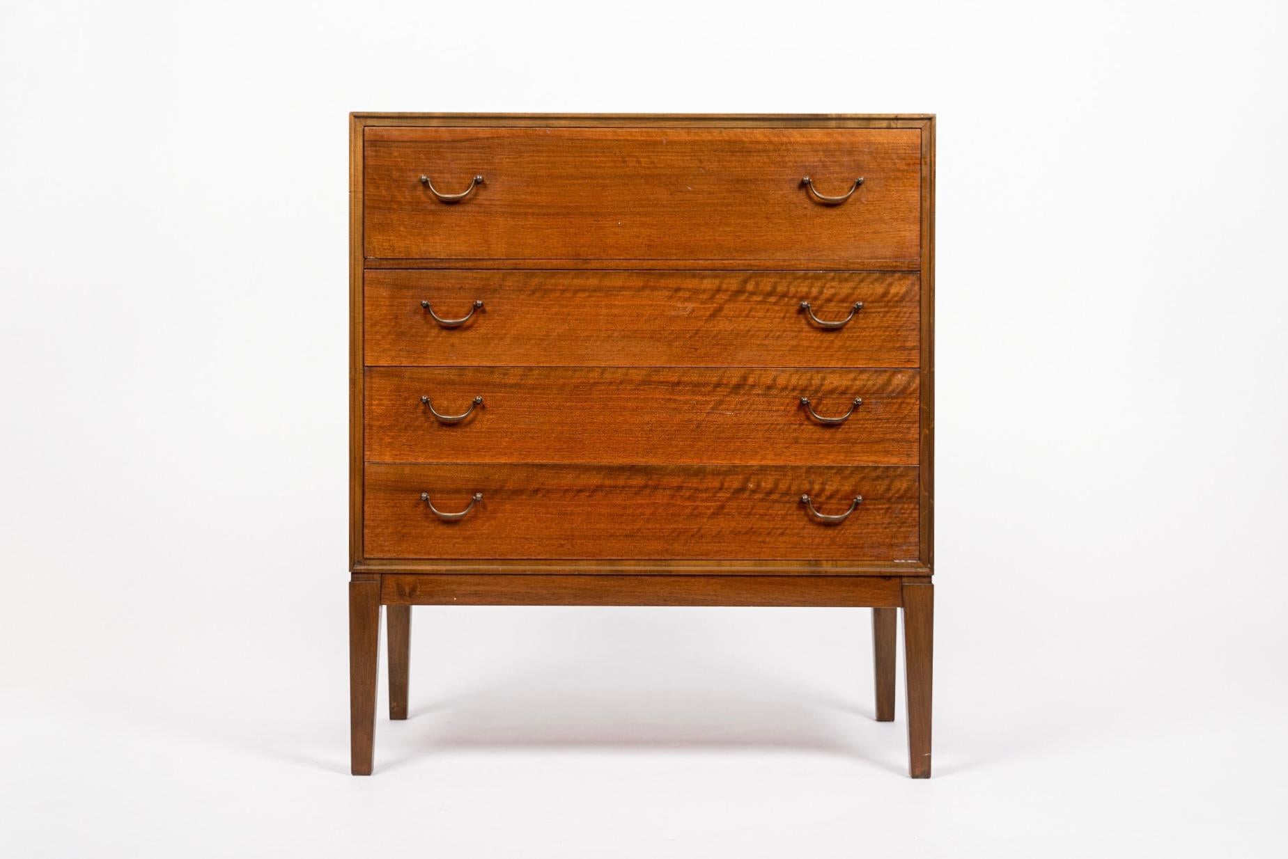 This vintage mid century Danish modern cabinetmaker vanity dresser in the style of Frits Henningsen is circa 1960. Expertly crafted from walnut wood, this unique cabinet has four spacious dovetailed drawers with original hanging brass handles and