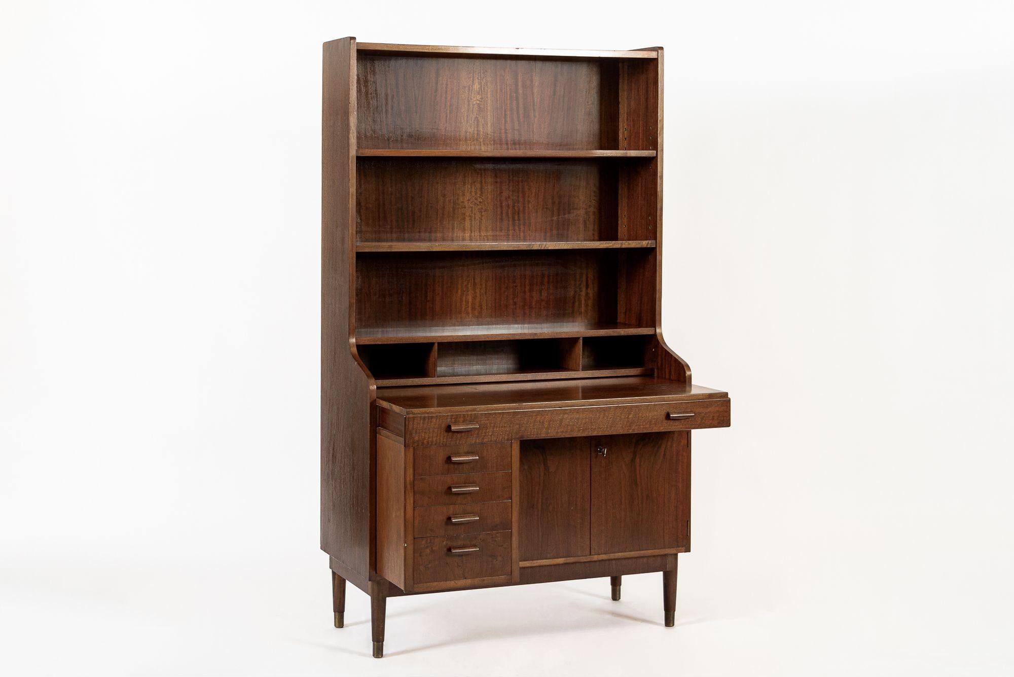 Questa scrivania e libreria vintage di metà secolo in legno di noce è del 1960 circa e presenta un formato unico con una sezione di cassetti inferiore che si estrae come un'unità completa, trasformando il mobile in una scrivania. Il mobile è ben
