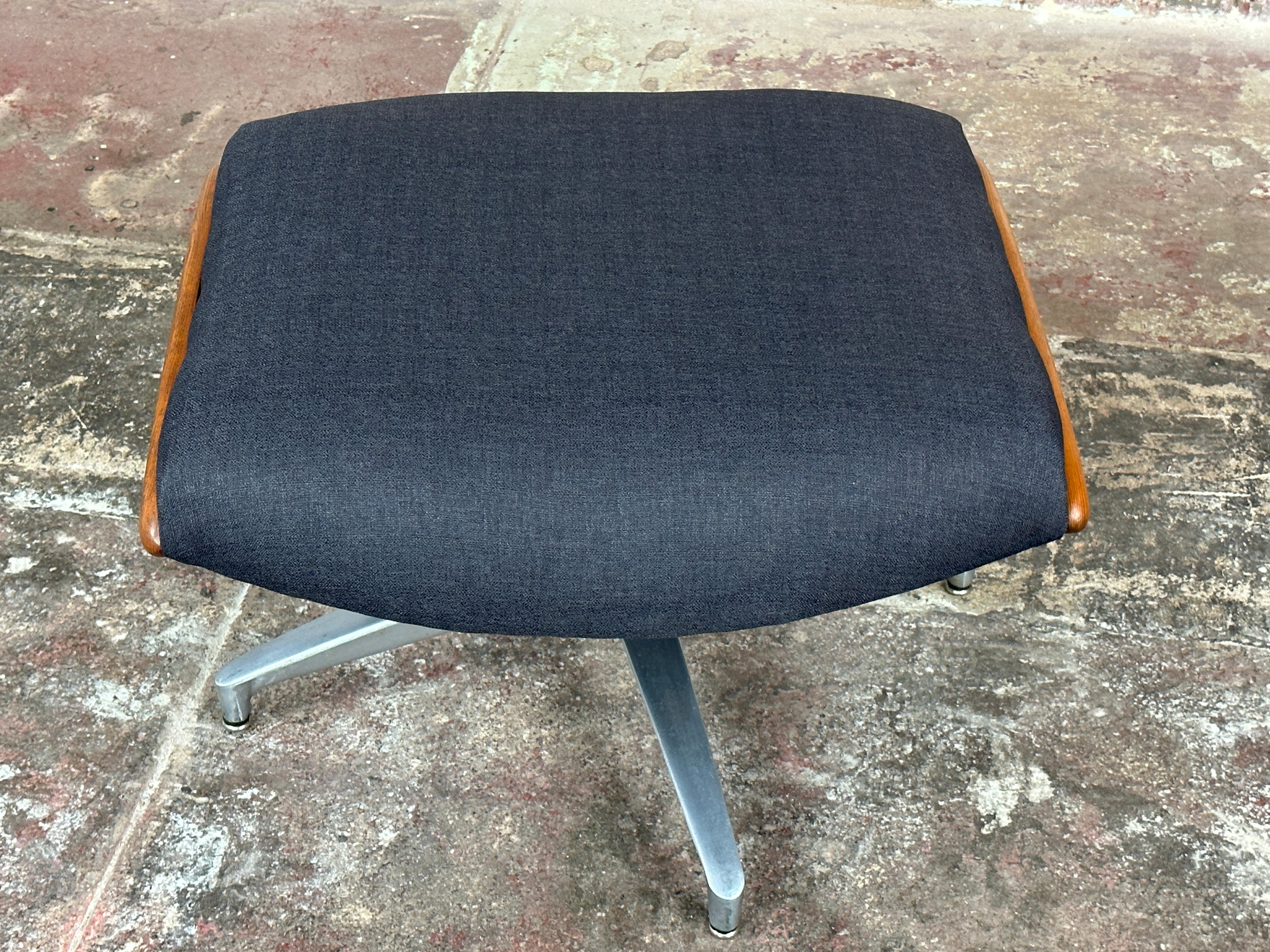 Inspired by the timeless designs of Charles Eames, this Mid-Century Swivel Ottoman  combines simplicity and functionality.

A polished stainless steel base provides stability to this swivel ottoman, accentuating the dark blue-grey upholstered seat