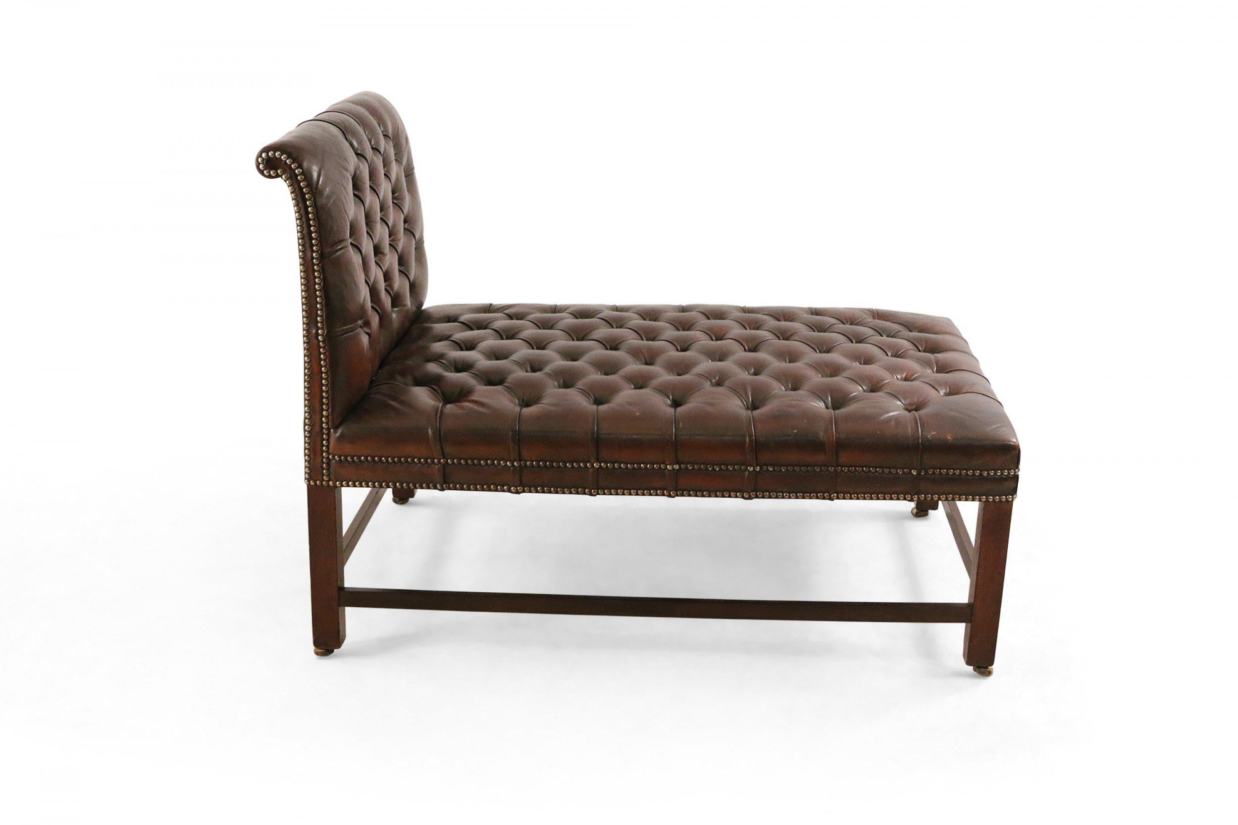 Mid-century dark brown leather psychiatrist's couch / chaise with button tufted upholstery, a backrest, and wooden frame legs.