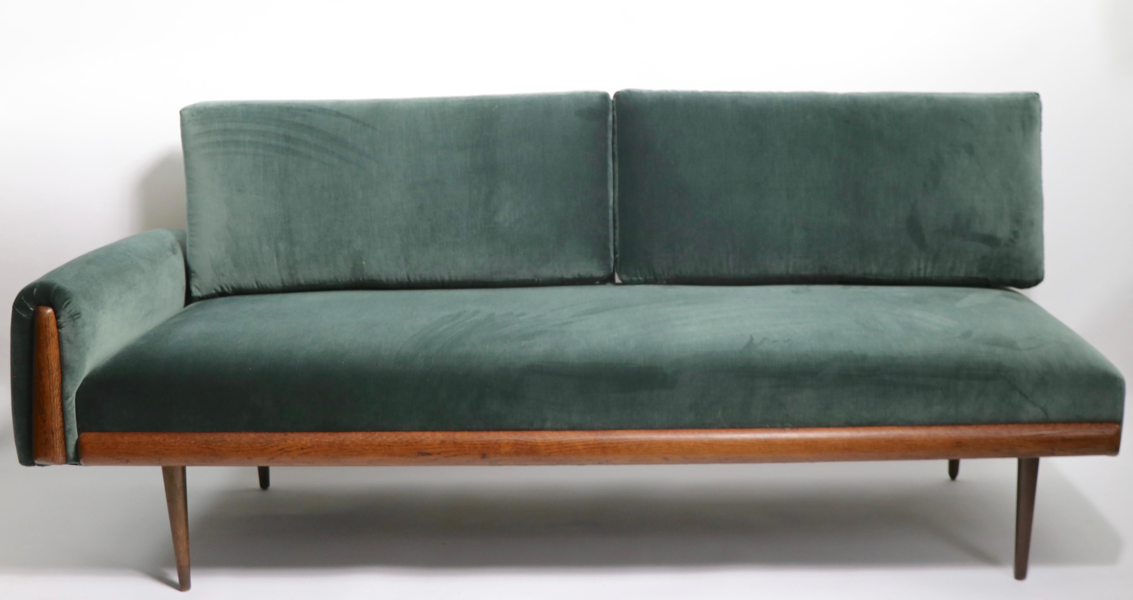 Classic mid-century daybed, sofa in excellent restored condition. The sofa has an asymmetrical design, having an armrest on one side ( 23.5 H in. ) and an open end on the other, on tapered pole legs with decorative wood trim.