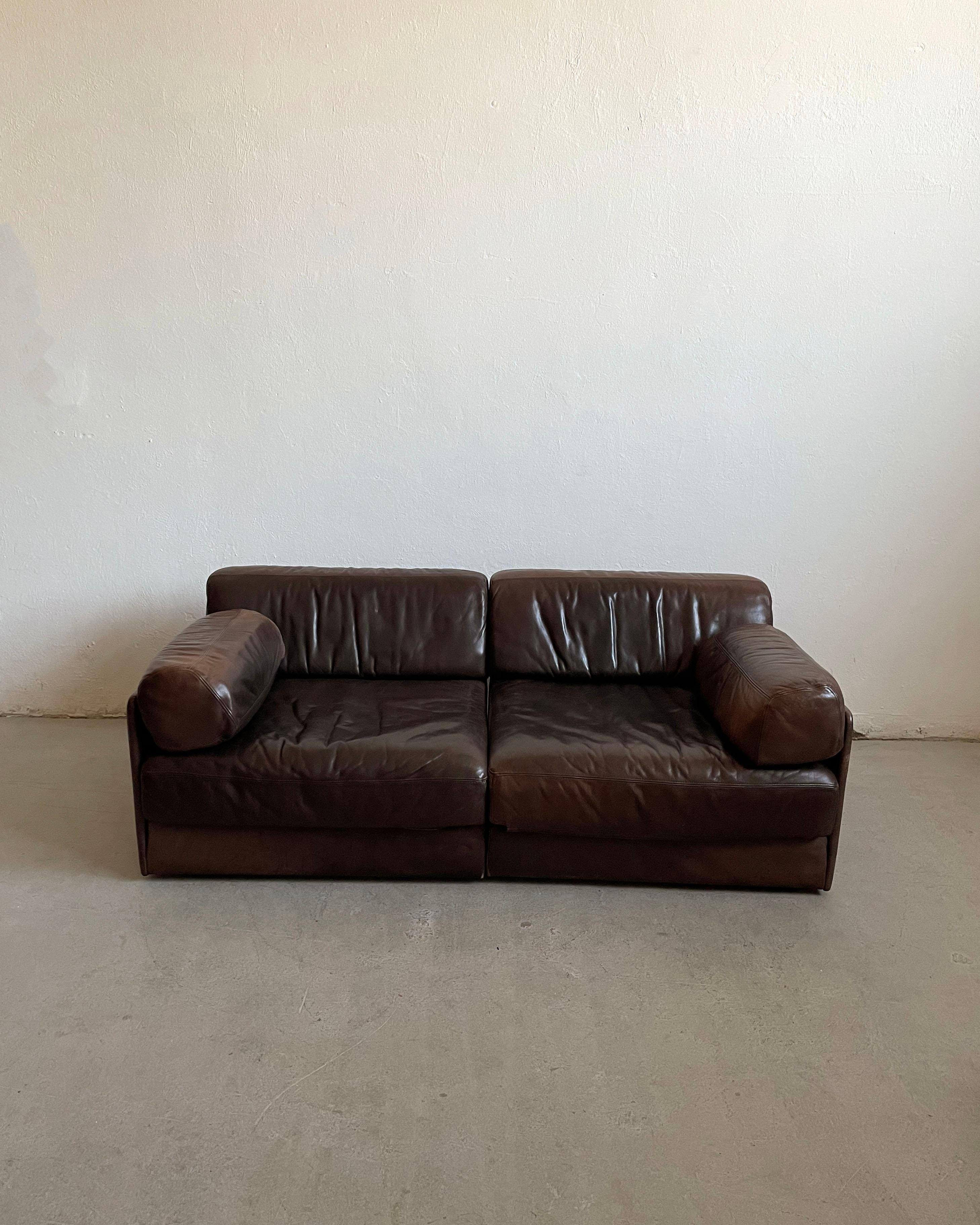 Vintage De Sede 2-piece modular sofa bed, model 'DS-76', leather, fabric, foam, wooden frame, Switzerland 1970s.

Important : L'objet proposé à la vente est en bon état d'origine. Le cuir présente une belle patine liée à l'âge. L'un des coussins de
