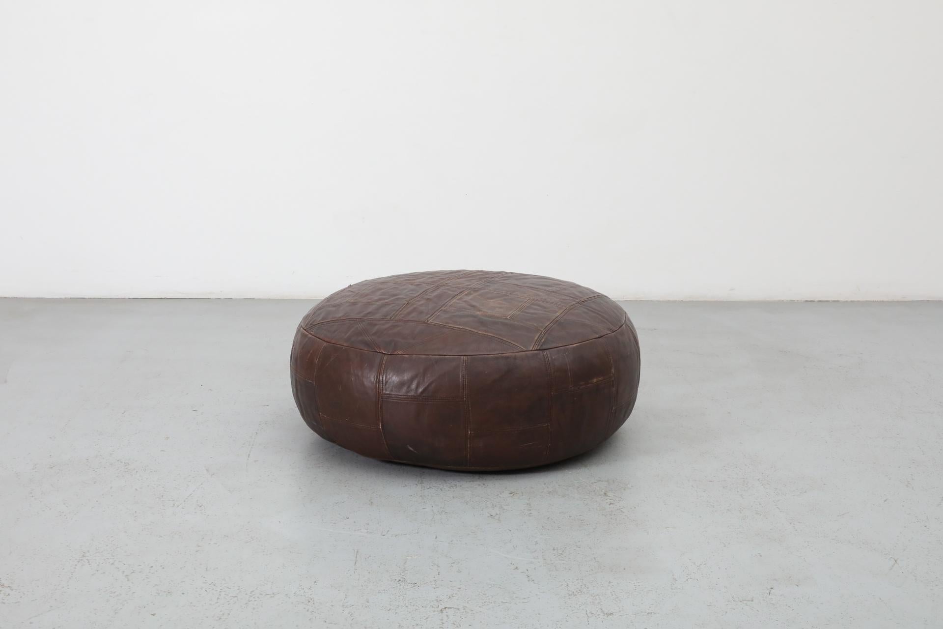 Dutch, Mid-Century De Sede inspired brown leather stitched patchwork ottoman. This lovely, large and heavy piece is in original condition with some visible wear and a rich, deep patina consistent with its age and use.
