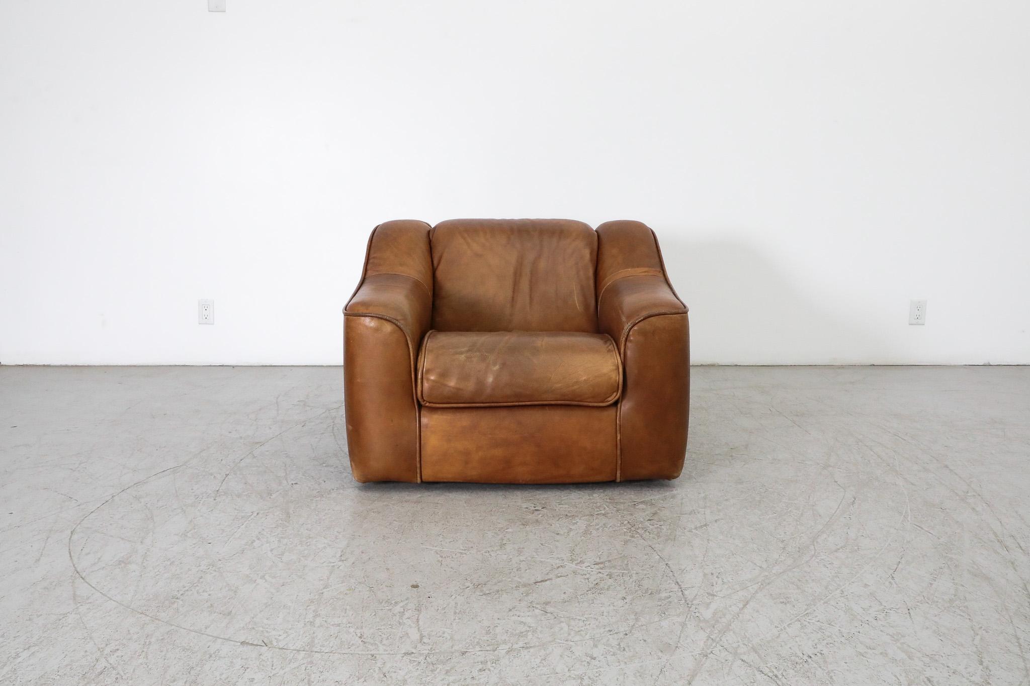 Incredible, Mid-Century, De Sede style, cognac leather lounge chair. Beautiful design with thick leather upholstery and comfortable, high arm rests. In original condition with complimentary visible patina and some wear consistent with age and