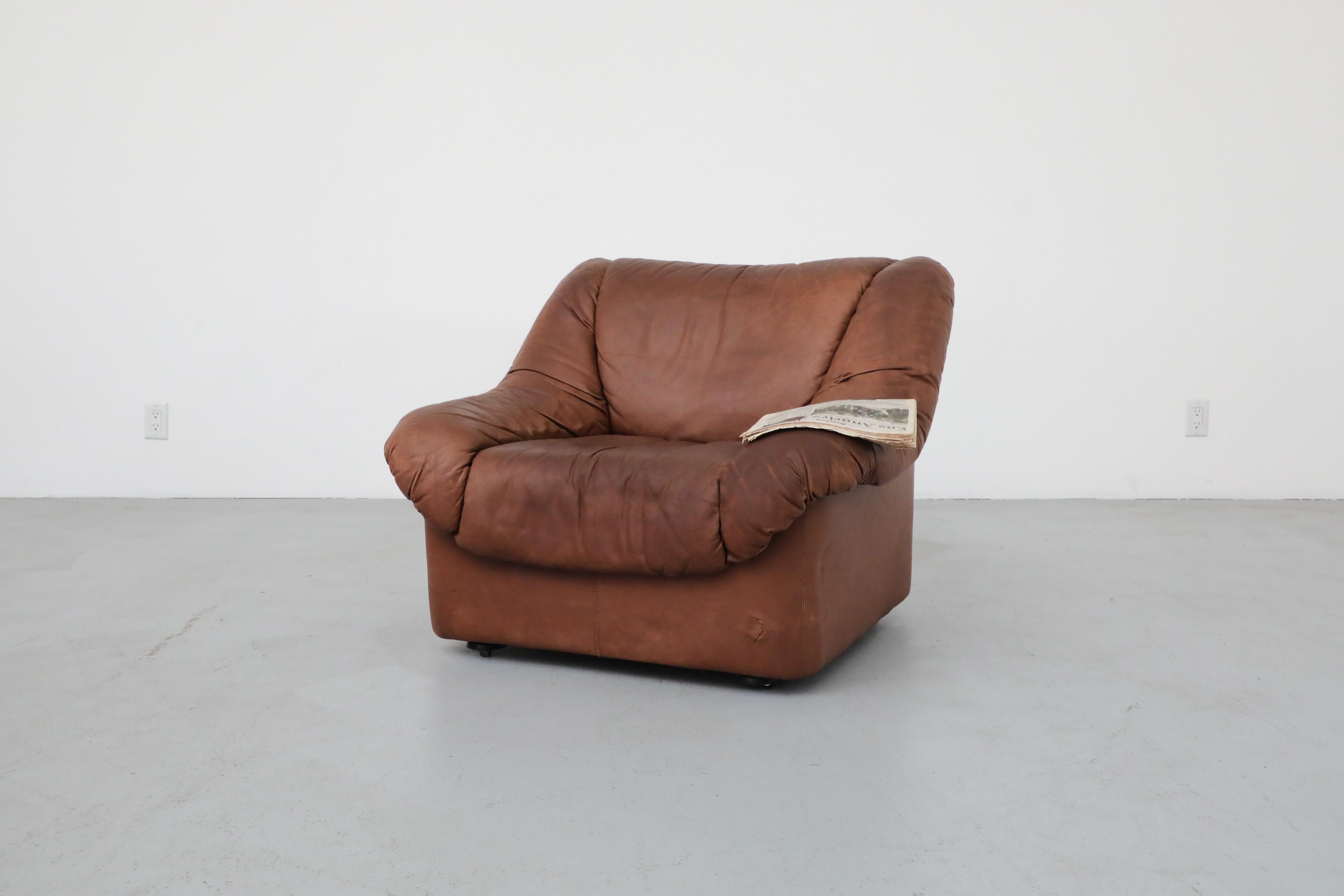 De Sede style tobacco leather lounge chair. In original condition with visible wear including scratches to leather, a small tear on the front and sun fading. Wear is consistent with its age and use. Matching modular sectional sofa (LU922439756142)
