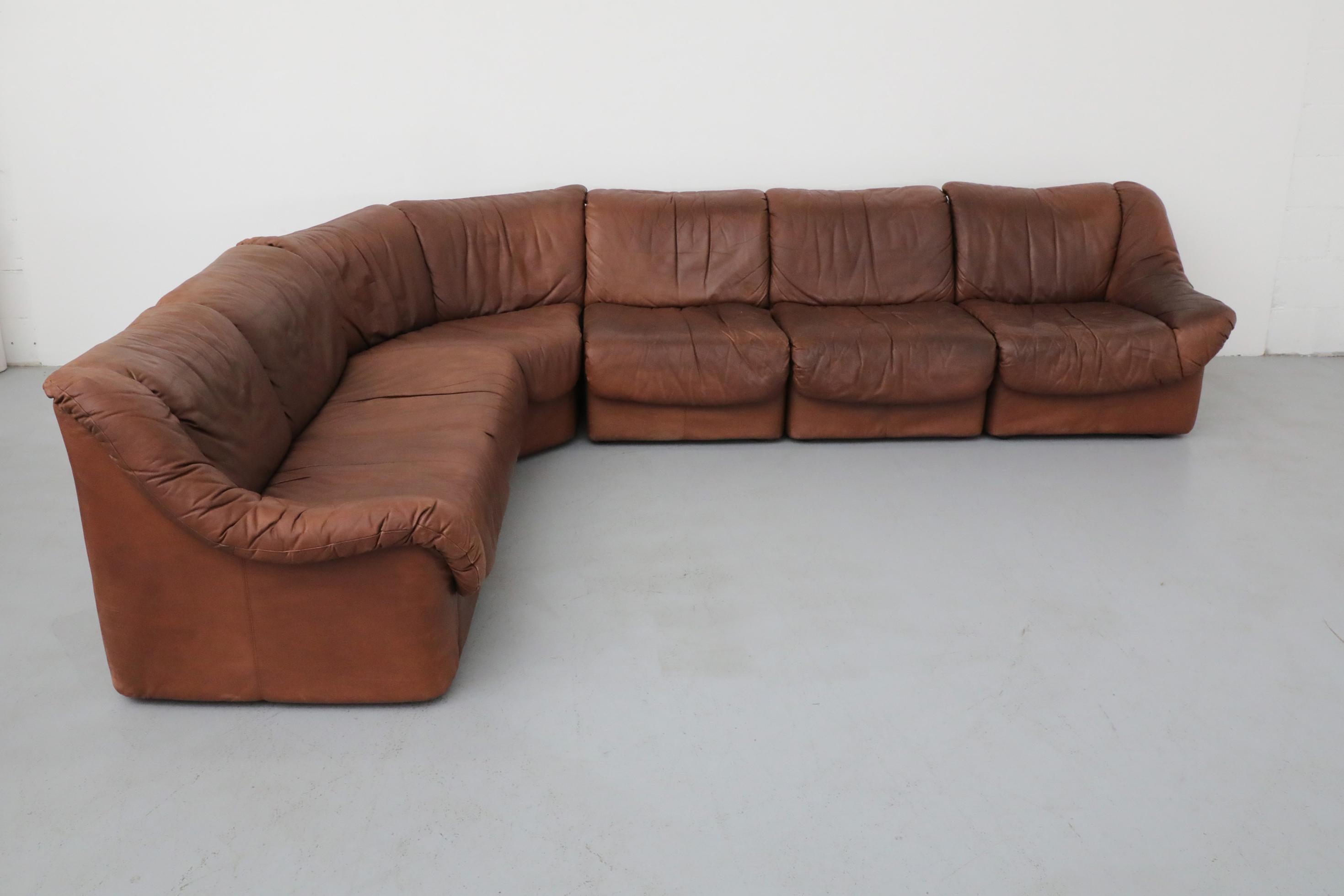 Canapé sectionnel modulable 5 pièces en cuir tabac de style De Sede composé des pièces suivantes : un coin incurvé, deux monoplaces sans accoudoir, un monoplace avec accoudoir à droite et un biplace avec accoudoir à gauche. En état d'origine avec