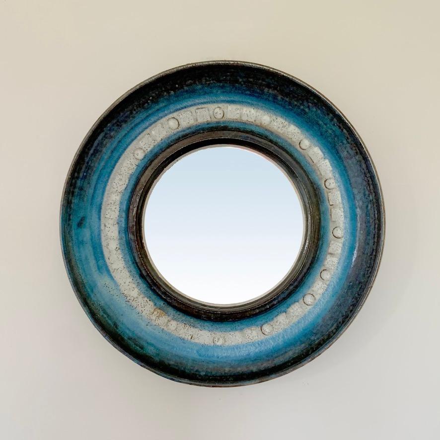 Mitte des Jahrhunderts  dekorativer runder Wandspiegel, um 1960, Frankreich.
Emaillierte Keramik, leuchtendes Blau, Creme und Brauntöne.
Abmessungen: Gesamtdurchmesser: 22 cm (8, 66 in), Durchmesser des verspiegelten Glases: 12 cm (4,72 in), d: 3 cm