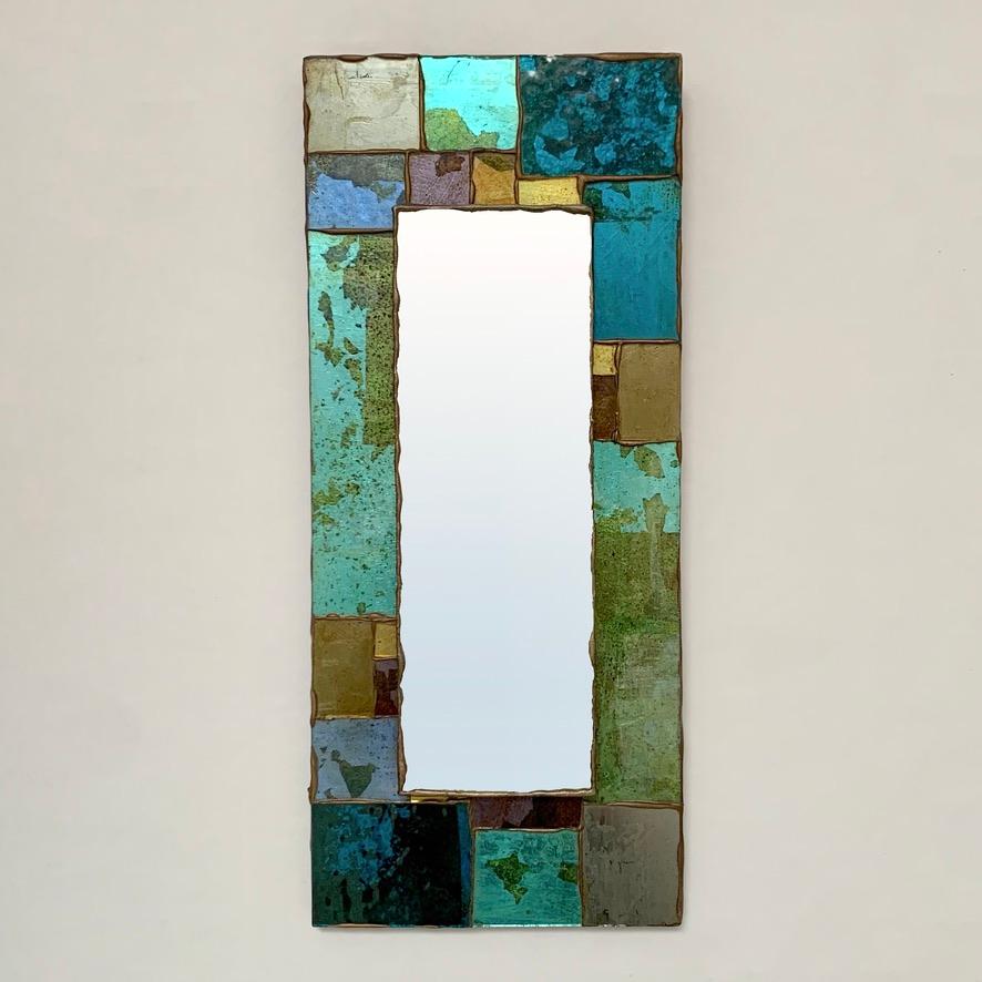 Hochdekorativer rechteckiger Wandspiegel, um 1970, Frankreich.
Mosaik aus farbigem Glas, bearbeitet mit Blattgold und -silber.
Zarte Blau-, Grün-, Ocker- und Violetttöne.
Abmessungen: 56 cm H (22,04 Zoll), 24 cm B (9,44 Zoll), 3 cm T (1,18