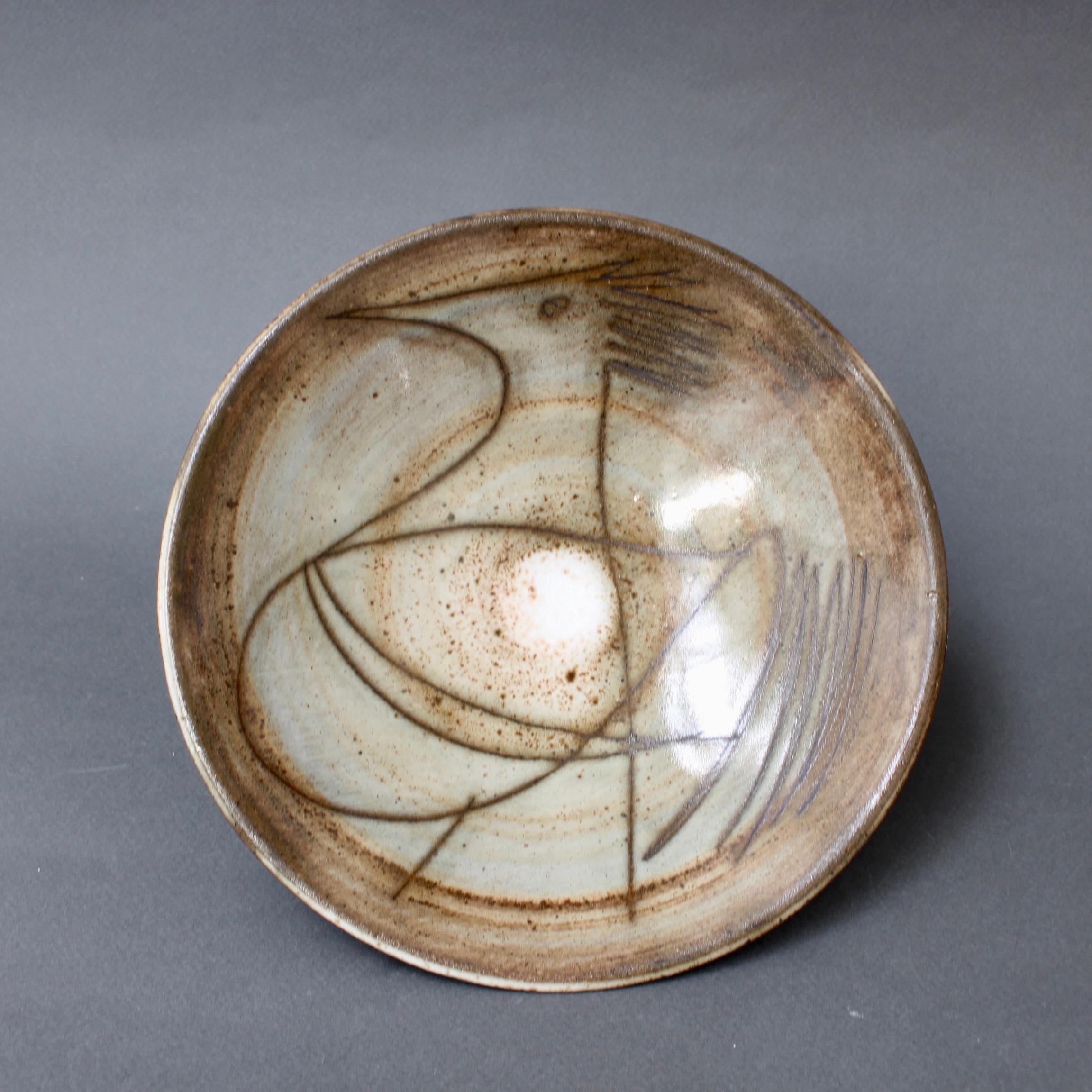 Midcentury decorative dish (circa 1960s) by Jacques Pouchain - Atelier Dieulefit. This elegant bowl, elevated by a small circular base, was created in Pouchain's trademark tones of brown. The bowl's glazed face is decorated with one of Pouchain's