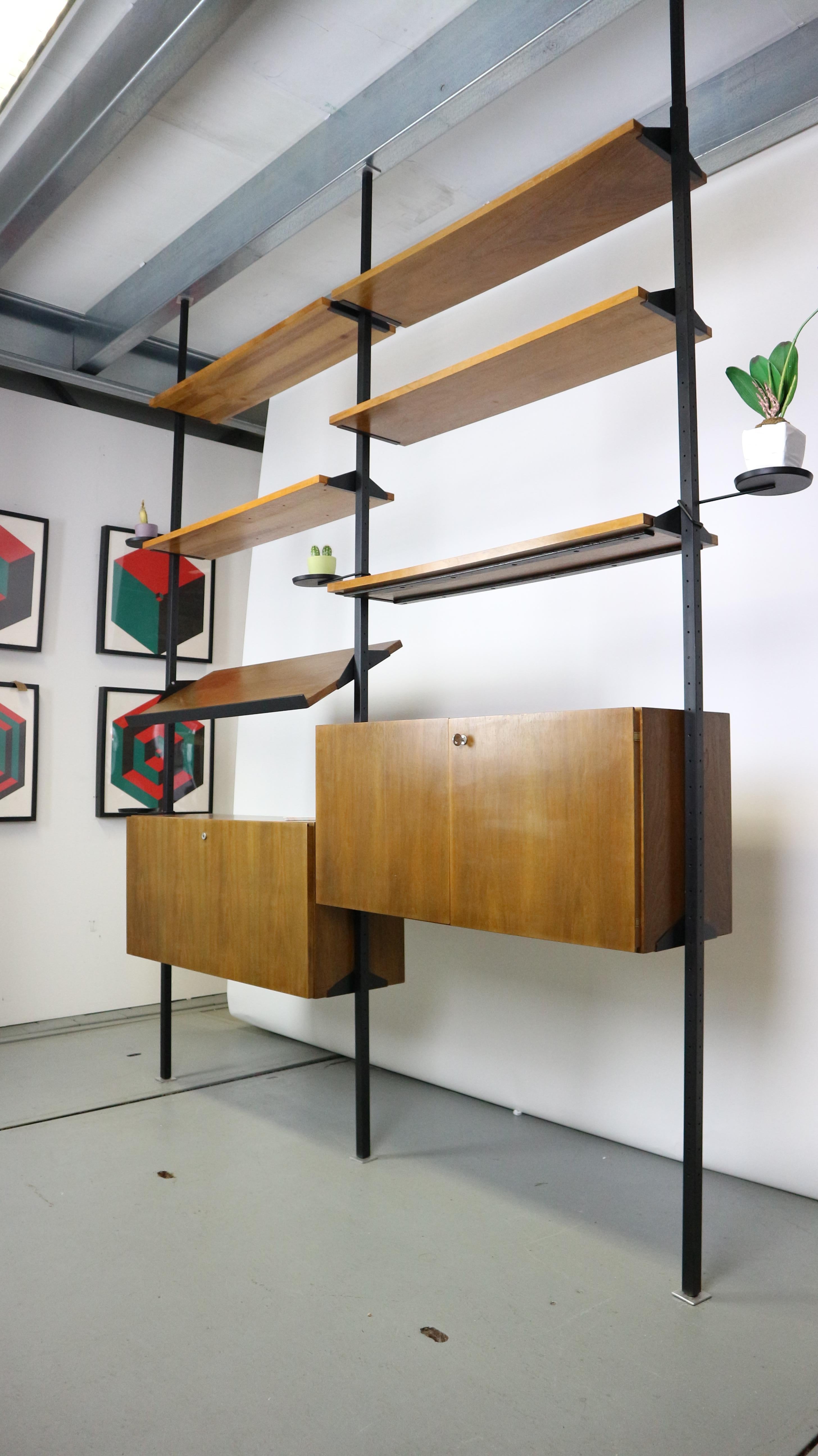 Great shelving unit is produced in the 1960s. German manufacturing. 
Made of black metal and walnut wood veneer.
This system is perfect to use as a room divider or shelving storage unit.
The metal feet has to be attached floor to ceiling. High is
