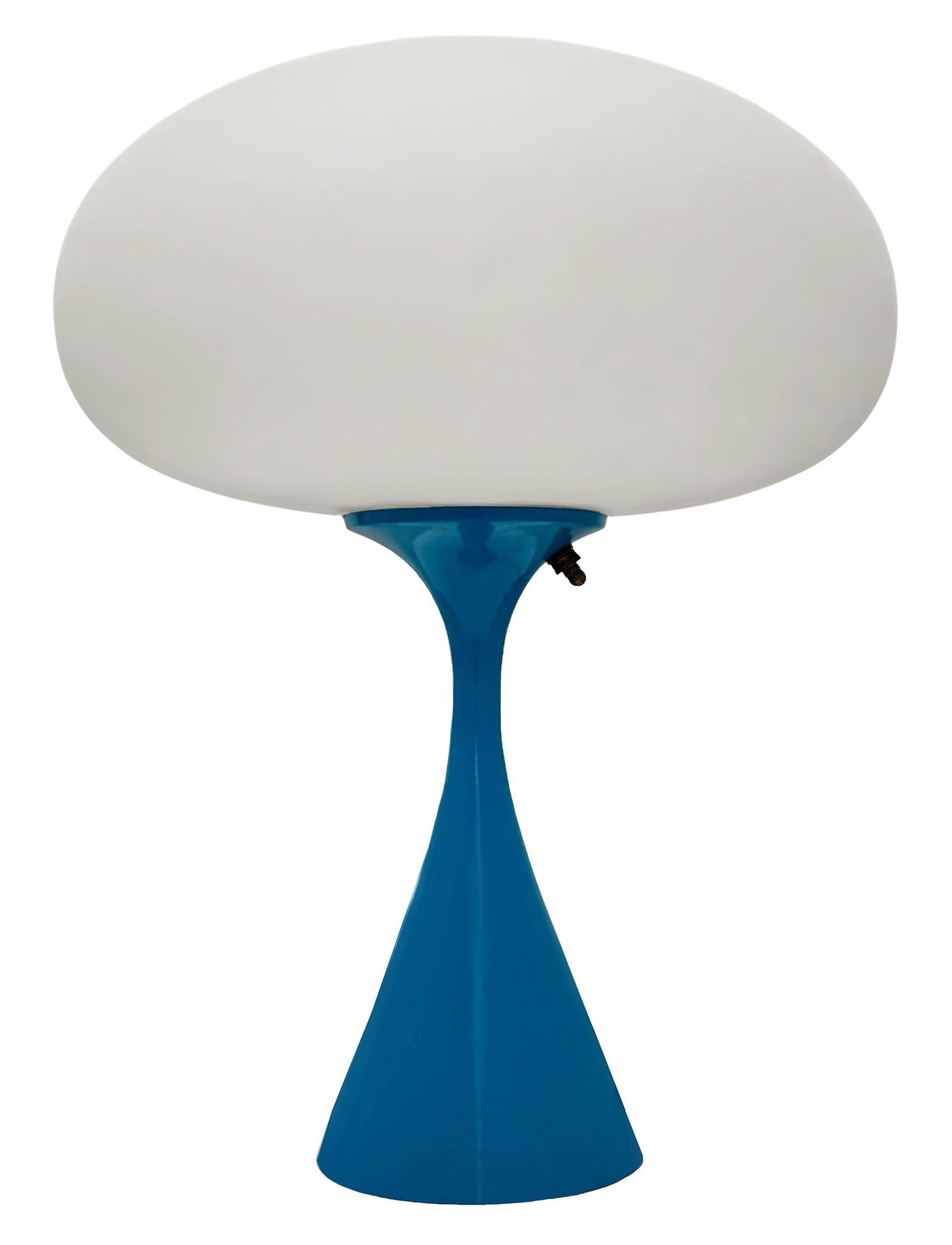 THIS ITEM IS ELIGIBLE FOR FREE SHIPPING!

A sleek stemlite table lamp made by Design Line. It features a cast aluminum main base in a conical form. The lamp base is finished in a classic retro blue color. The frosted glass lamp shade is hand blown