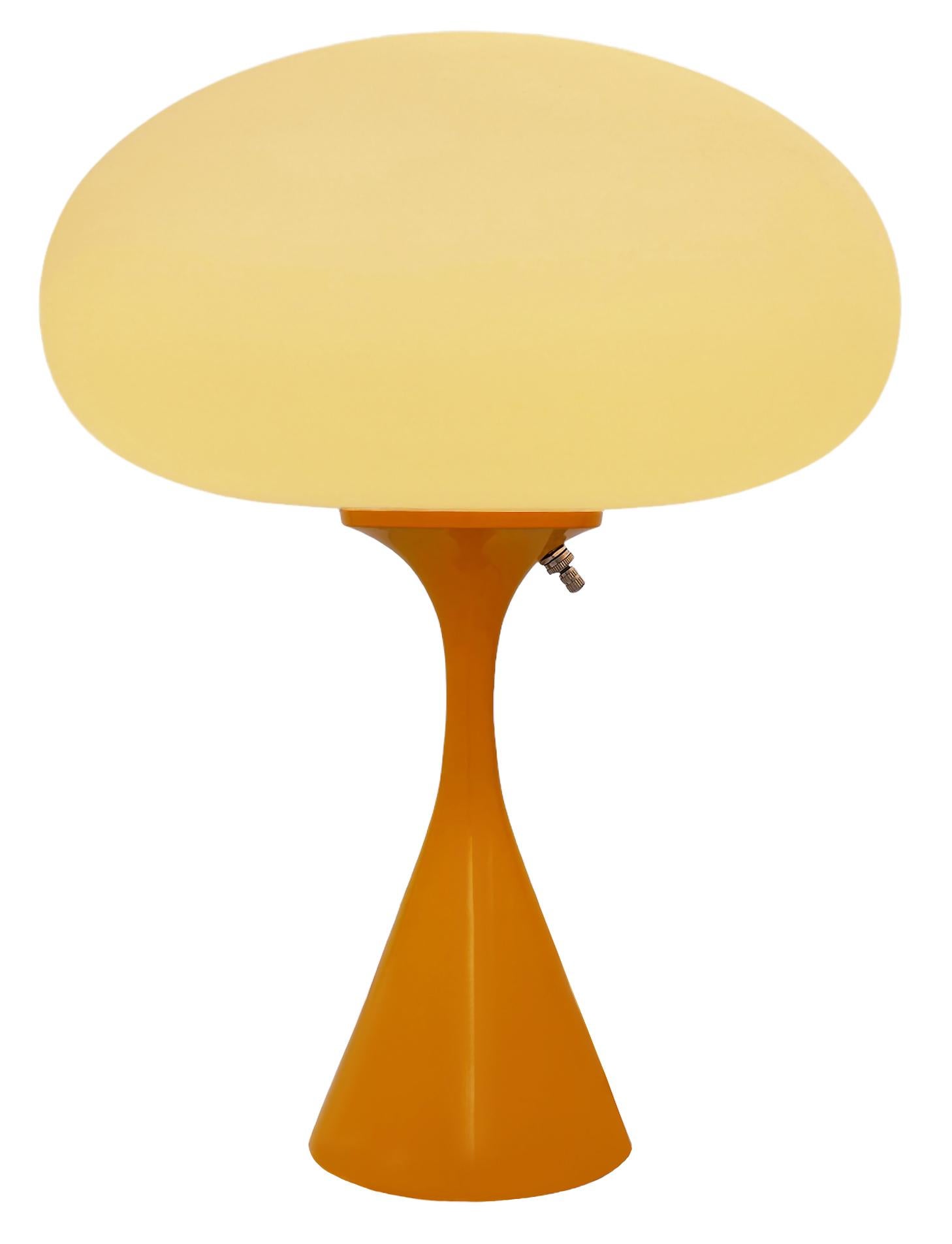 THIS ITEM IS ELIGIBLE FOR FREE SHIPPING!

A sleek stemlite table lamp made by Design Line. It features a cast aluminum main base in a conical form. The lamp base is finished in a retro mango orange color. The frosted glass lamp shade is hand blown