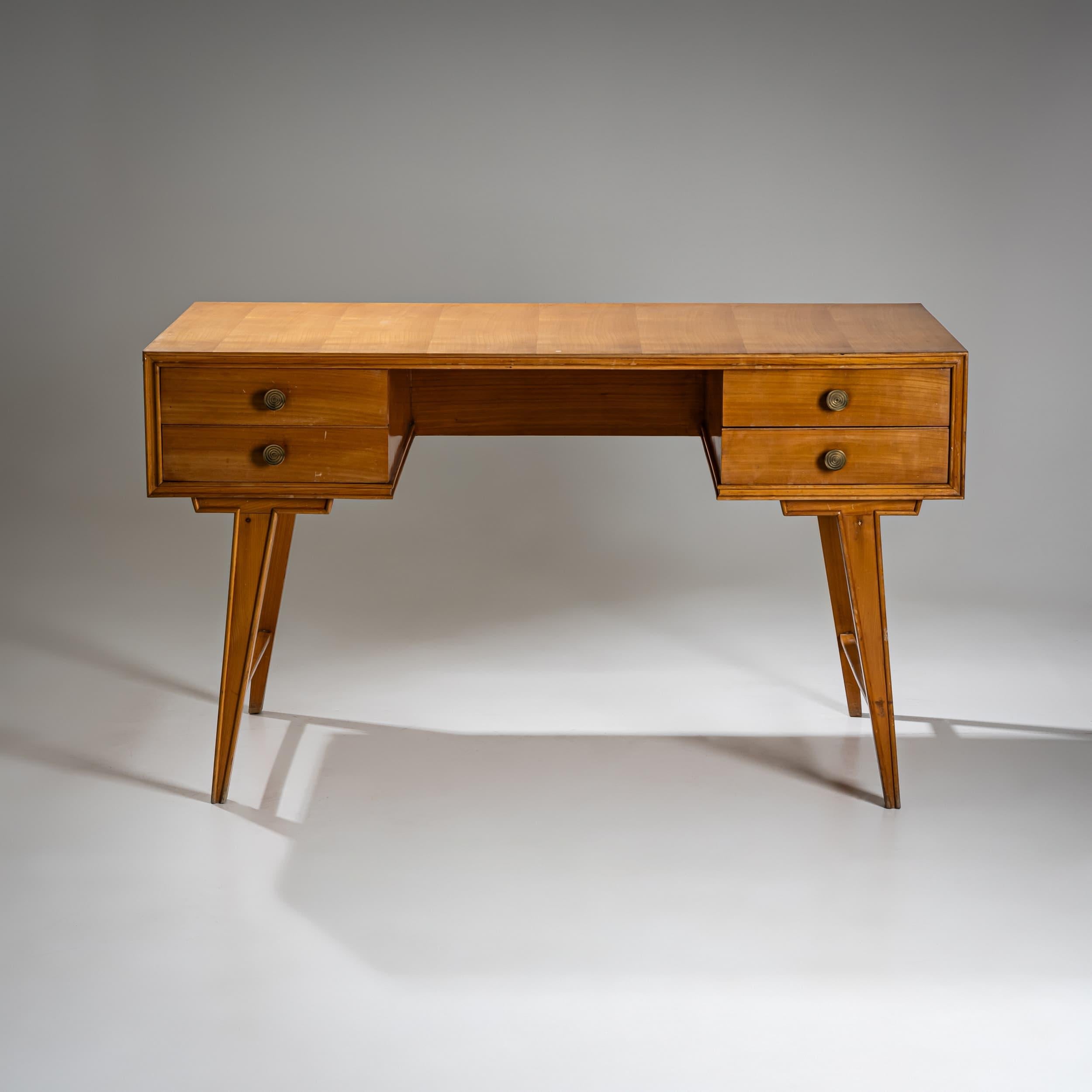 Mid-century style desk crafted from light-toned wood, featuring clean lines and tapered, slightly splayed legs. The desk is equipped with four drawers adorned with round brass handles and offers a well-balanced working surface.