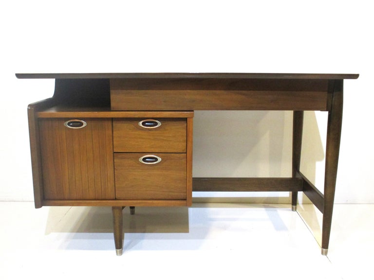 A nice sized Mid Century mahogany desk that is very stylish and very useable with a true file drawer, two small drawers a long centered drawer and a file cubie to the upper left side under the floating top. The desk has pulls that are a bronzed
