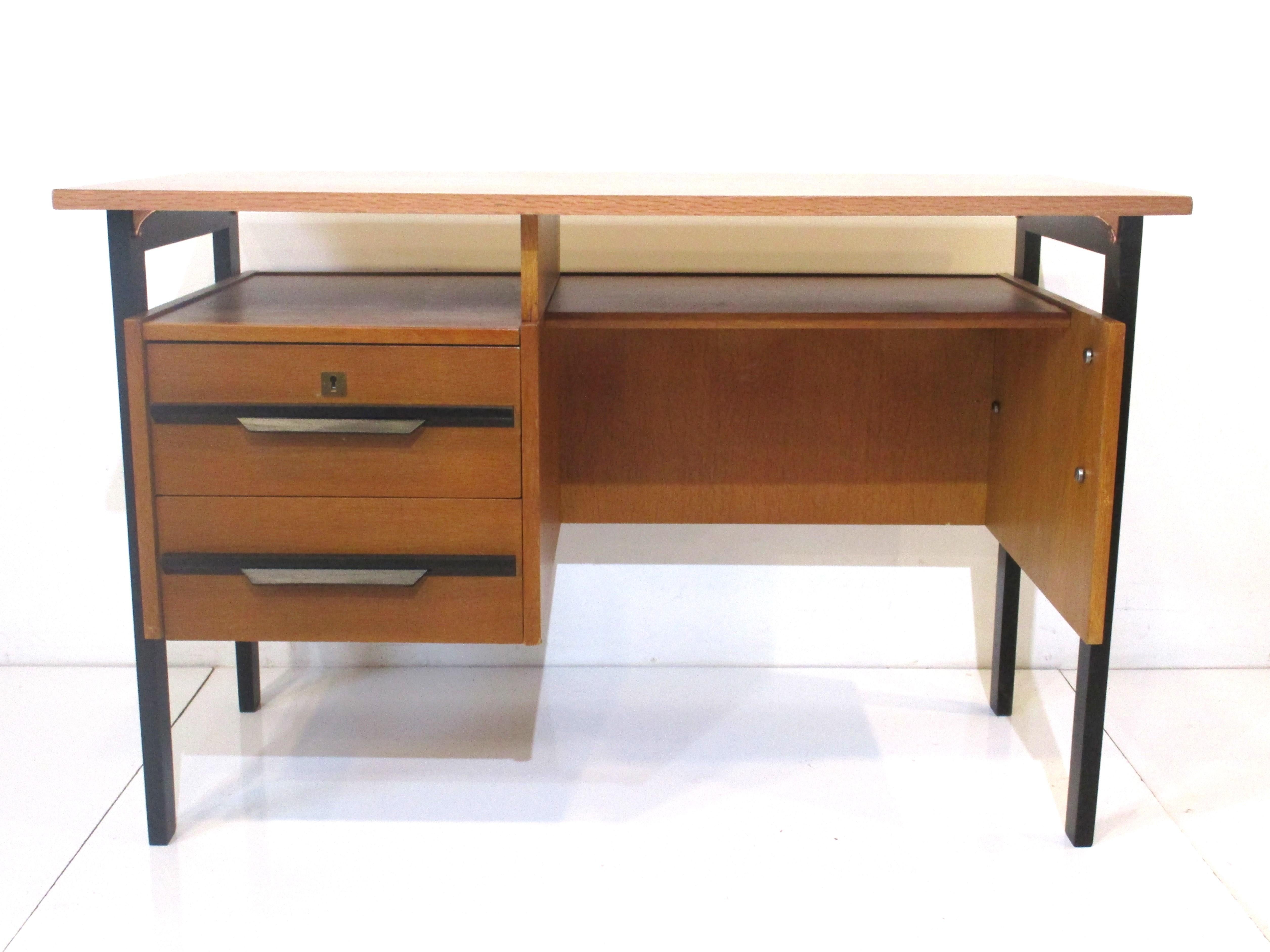 A very nice simple smaller sized writing desk with two drawers having bent wood handles and upper area storage shelve under the floating top . In the kneehole there's another set back storage area , the black contrasts with the honey colored wood of