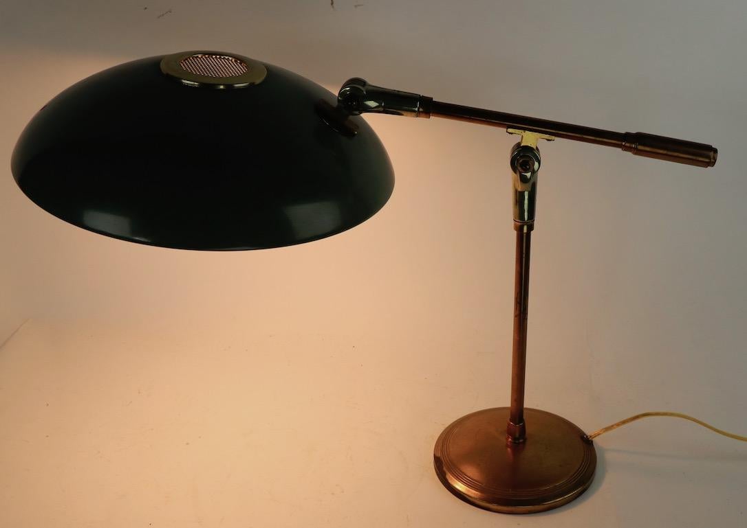 Mid-Century Modern adjustable desk lamp designed by Gerald Thurston for Lightolier. The lamp has a saucer disk shade ( 12 in diameter. ) which tilts and pivots, and the support arm ( 22 in L with shade ) will raise and lower, to position and direct
