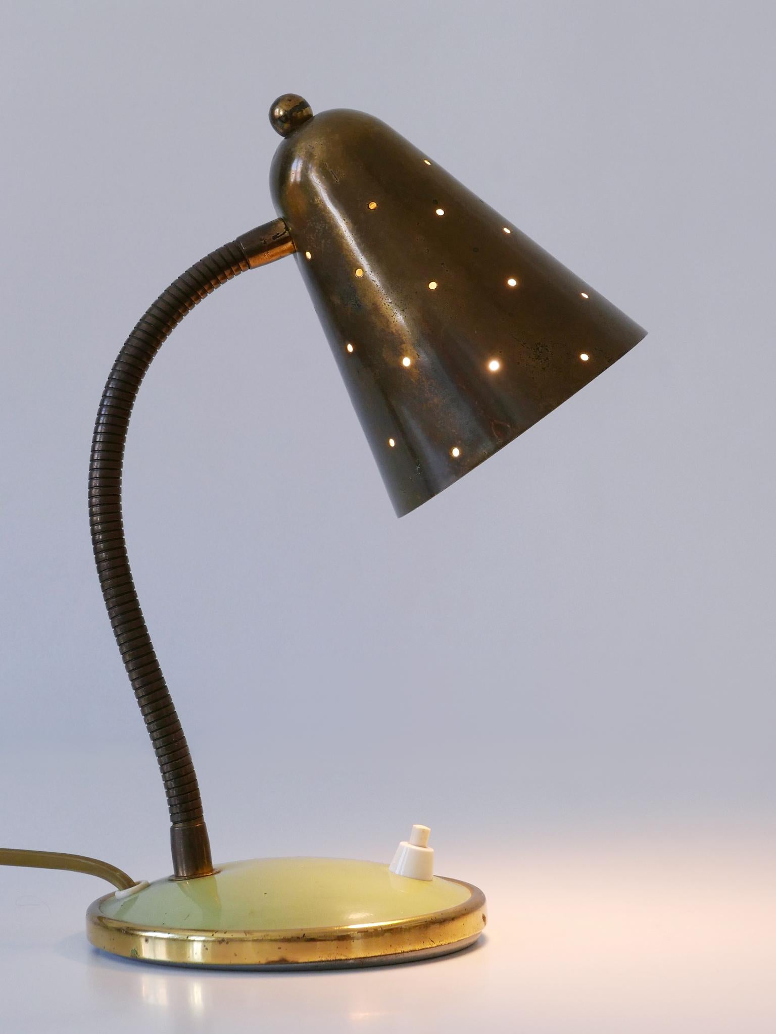 Rare et élégante lampe de bureau ou lampe de table à col de cygne du milieu du siècle dernier avec abat-jour conique en laiton perforé. Conçu et fabriqué par Vereinigte Werkstätten München, Allemagne, années 1960.

Réalisée en laiton et en métal, la