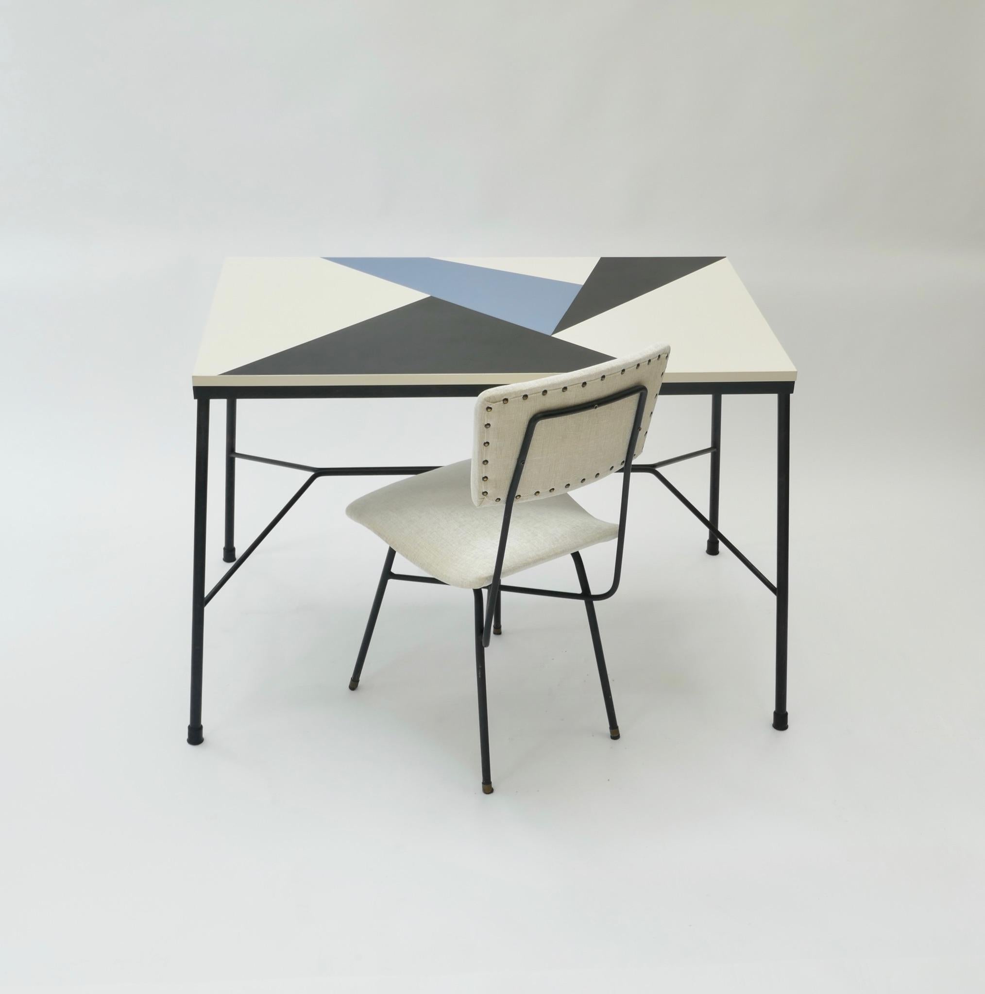 Midcentury desk with a black, white and blue melamine wood top and a white velvet chair with a black metal structure.