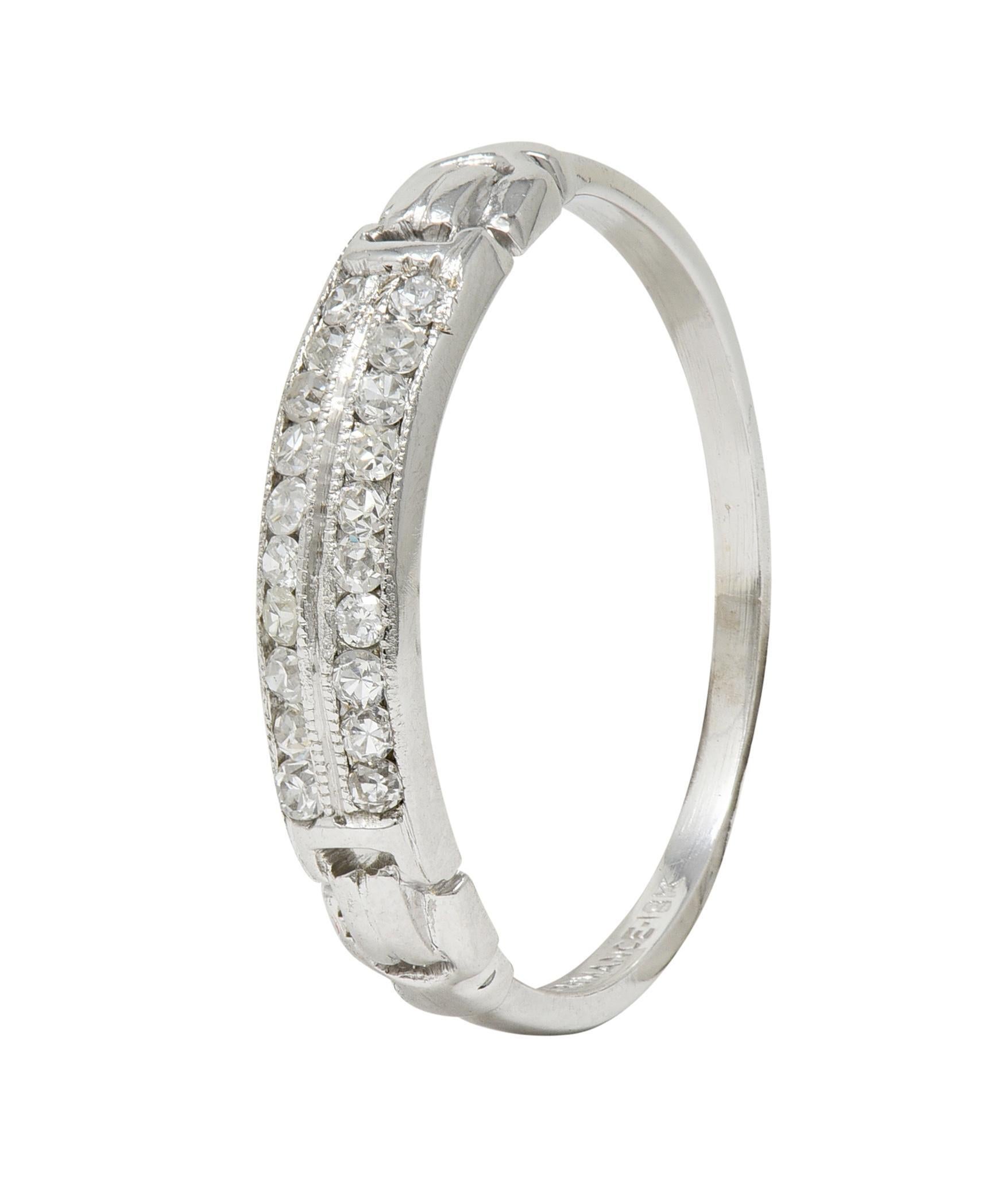 Centering two parallel rows of single cut diamonds channel set to front
Weighing approximately 0.20 carat total - H/I color with VS2 clarity 
Flanked by pierced buckle motif shoulders 
Accented by groove and milgrain detail
Stamped for 18 karat