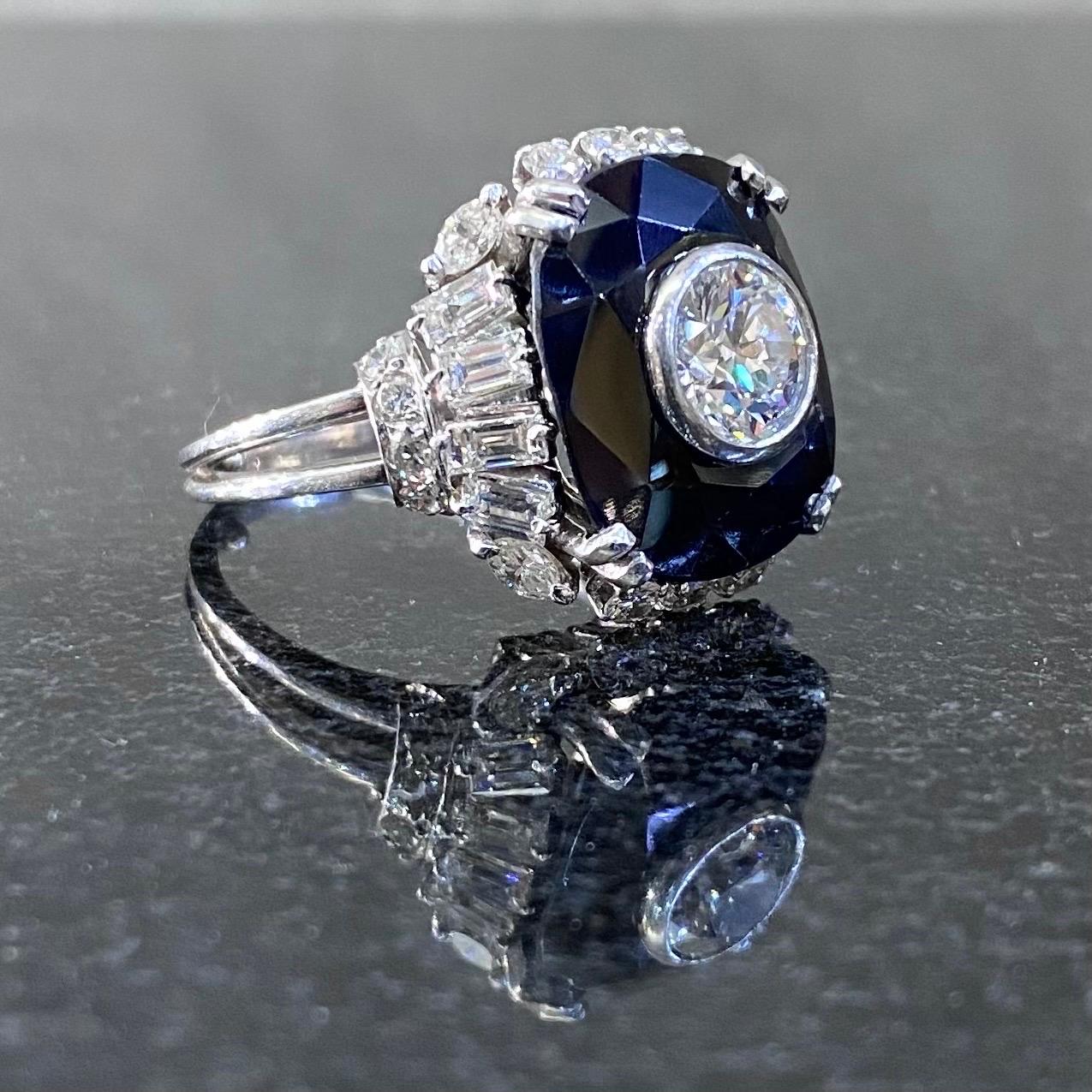 Mid-Century diamond and dark blue sapphire cocktail ring in platinum, Europe, 1950s/1960s. This ring features an elongated cushion-shape dark blue sapphire claw-set to the center and accented in the middle with a bezel-set round brilliant-cut