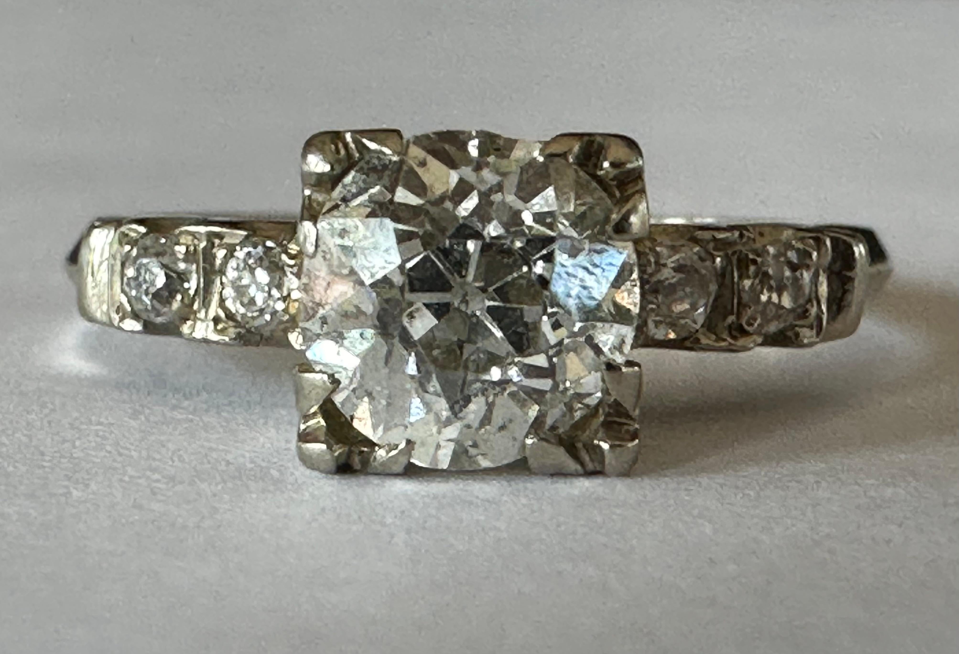Ein Diamant im alten europäischen Schliff von etwa 0,73 Karat steht im Mittelpunkt dieses wunderschönen Rings, der in den 1940er Jahren gefertigt wurde,  flankiert von vier kleineren Diamanten im alteuropäischen Schliff, zwei auf jeder Seite.