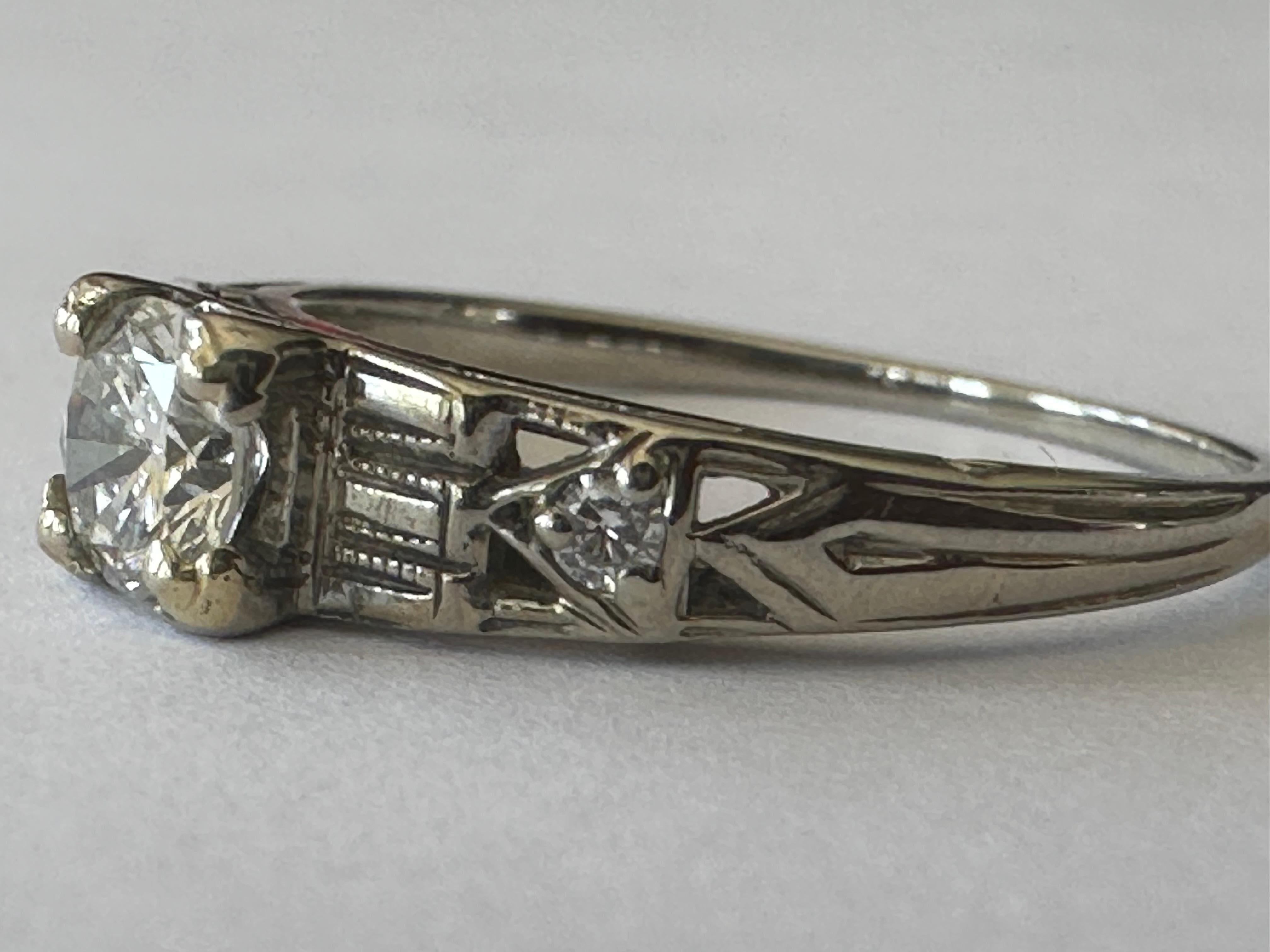 Fabriquée dans les années 1950, cette bague de fiançailles du milieu du siècle est conçue autour d'un diamant central de taille ancienne mesurant environ 0,35 carat, de couleur G et de pureté SI1, accentué par deux minuscules diamants de taille