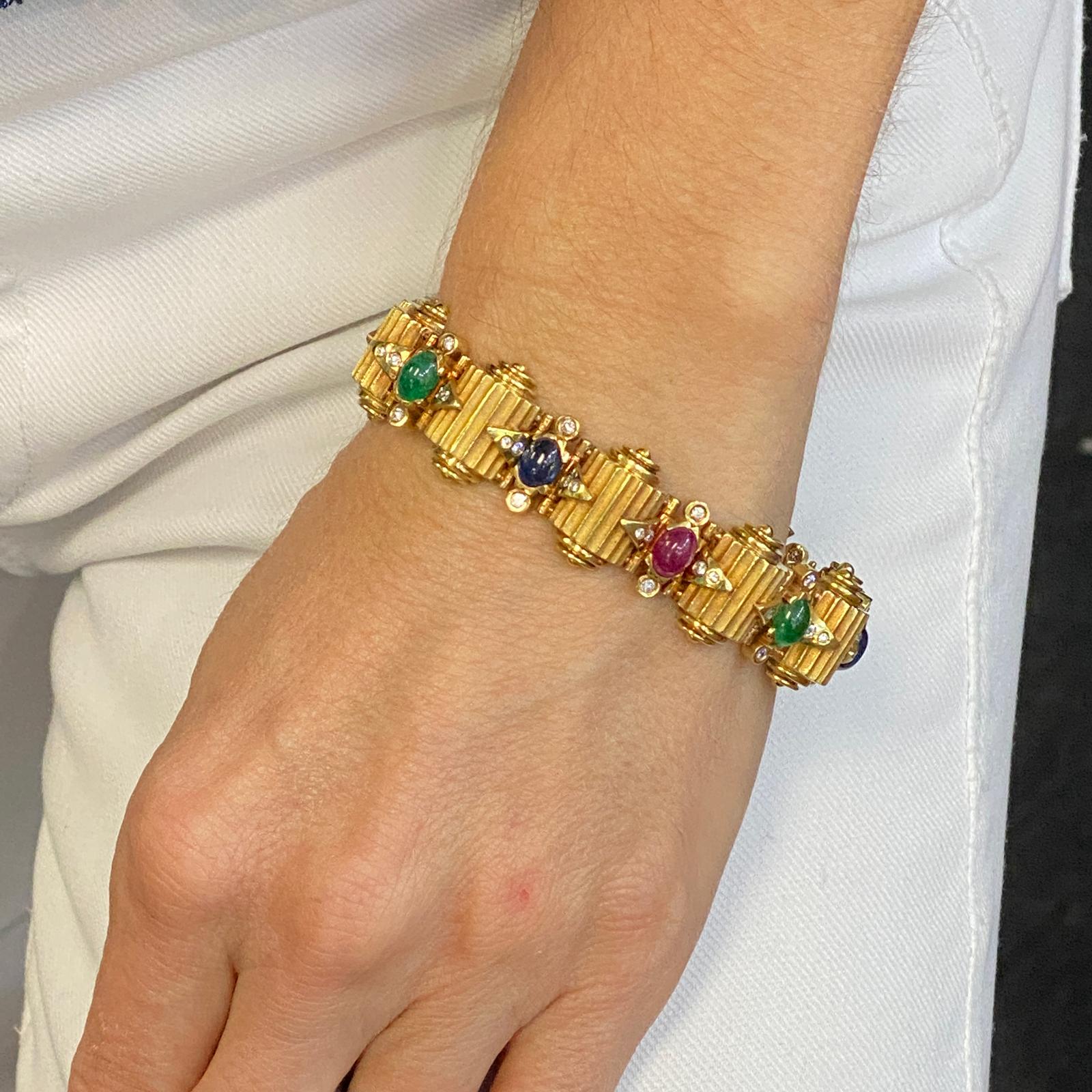 Fabulous diamond, emerald, ruby, and sapphire ribbed bracelet fashioned in solid 14 karat yellow gold. The bracelet features 60 round brilliant cut diamonds weighing approximately 1.00 CTW and graded G-H color and VS clarity. Another 10.00 carats of