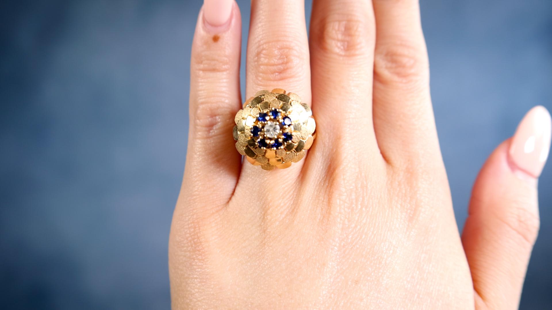 One Mid-Century Diamond Sapphire 18k Yellow Gold Cocktail Ring. Featuring one round brilliant cut diamond weighing approximately 0.15 carat, graded J color, I1 clarity. Accented by seven round brilliant cut sapphires with a total weight of