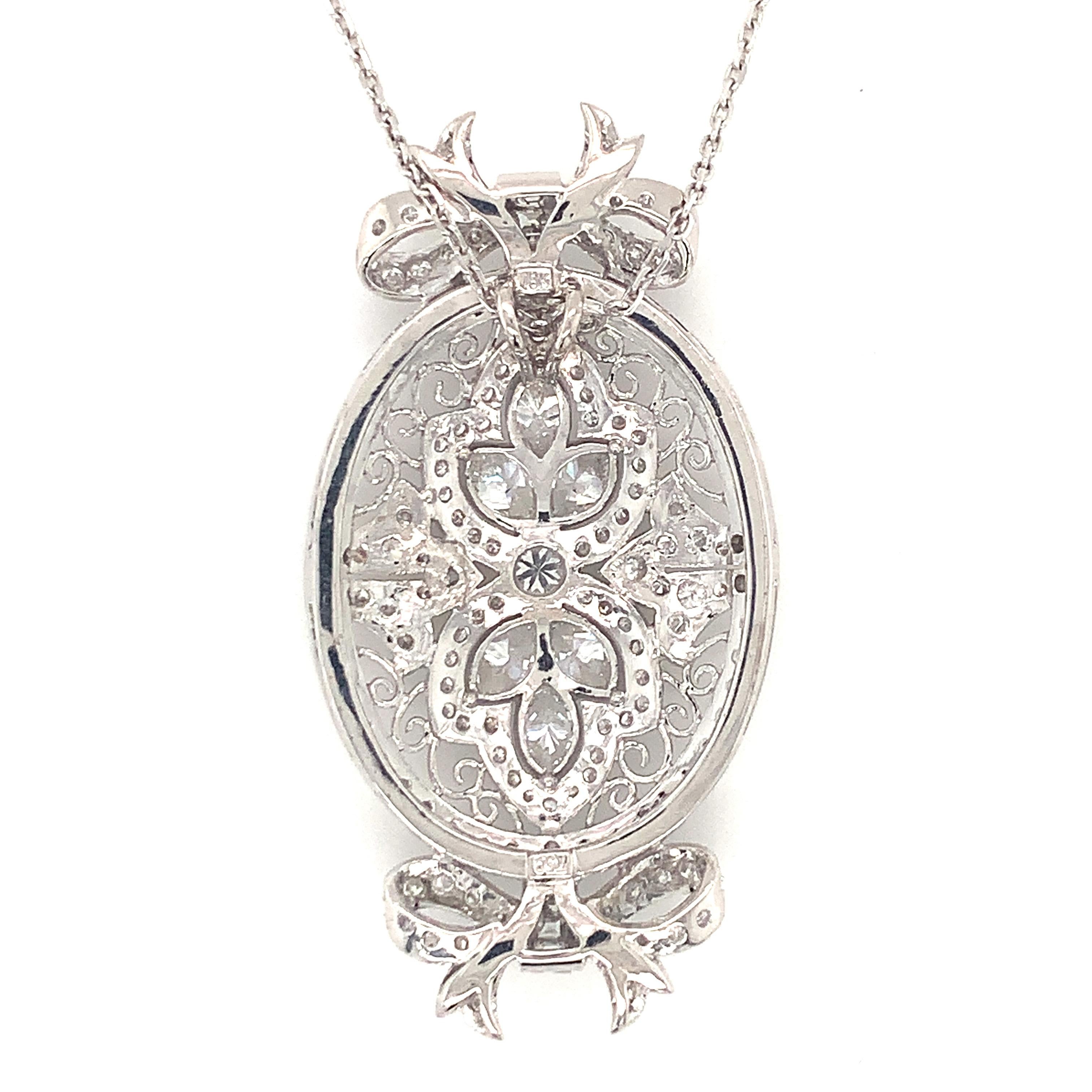 One mid-century diamond 18K white gold pendant featuring scroll work and a bow motif upon an oval-shaped pendant with 147 round brilliant cut, marquise brilliant, and baguette cut diamonds totaling 3 ct. Attached to a 14K white gold open link