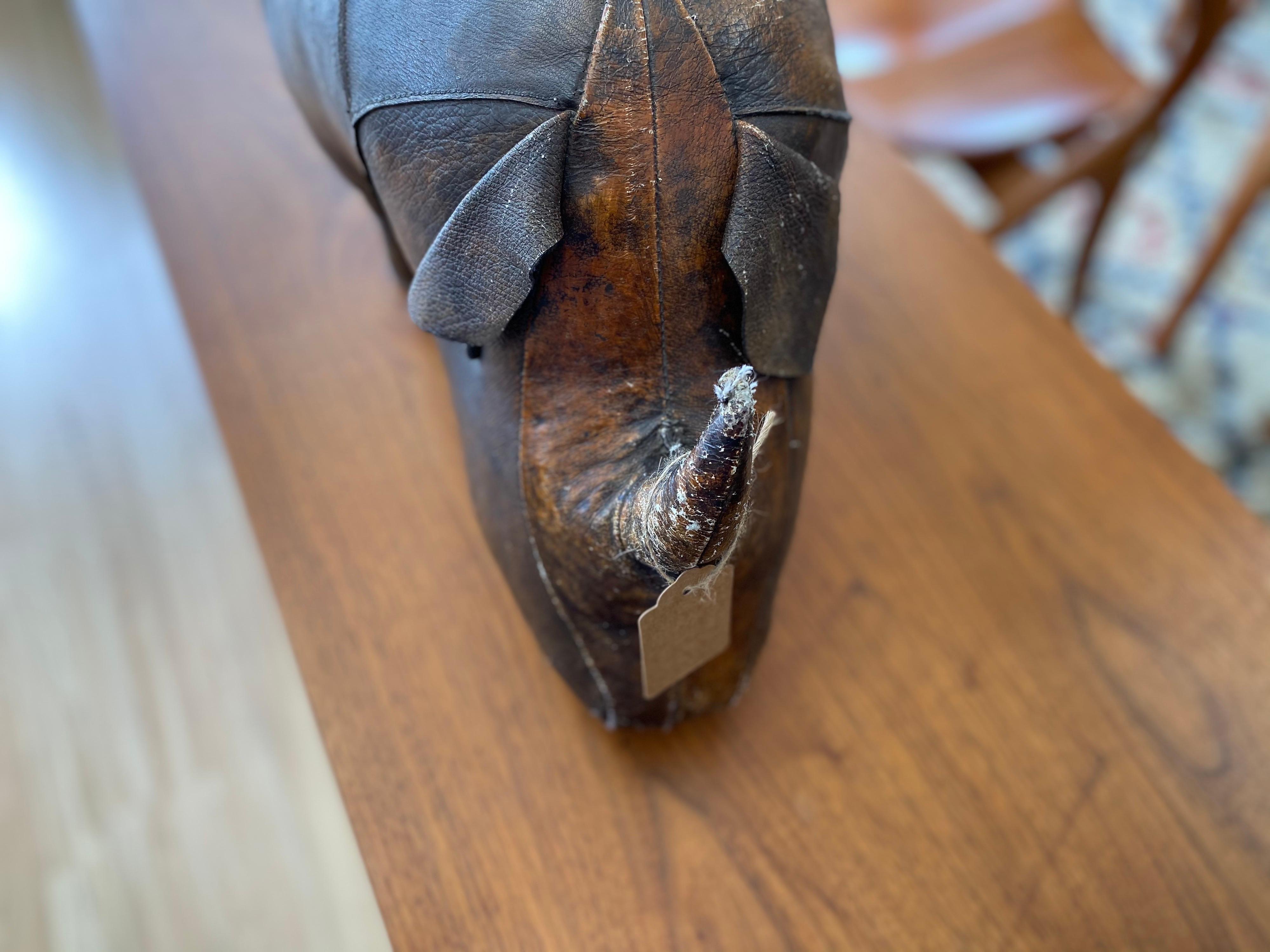 Vintage leather rhino decorative footstool designed by Dimitri Omersa for Abercrombie and Fitch, circa 1960s is hand-stitched and features aged leather. The horn, tail, and eyes are intact. Vintage leather footstool is structurally sound and a