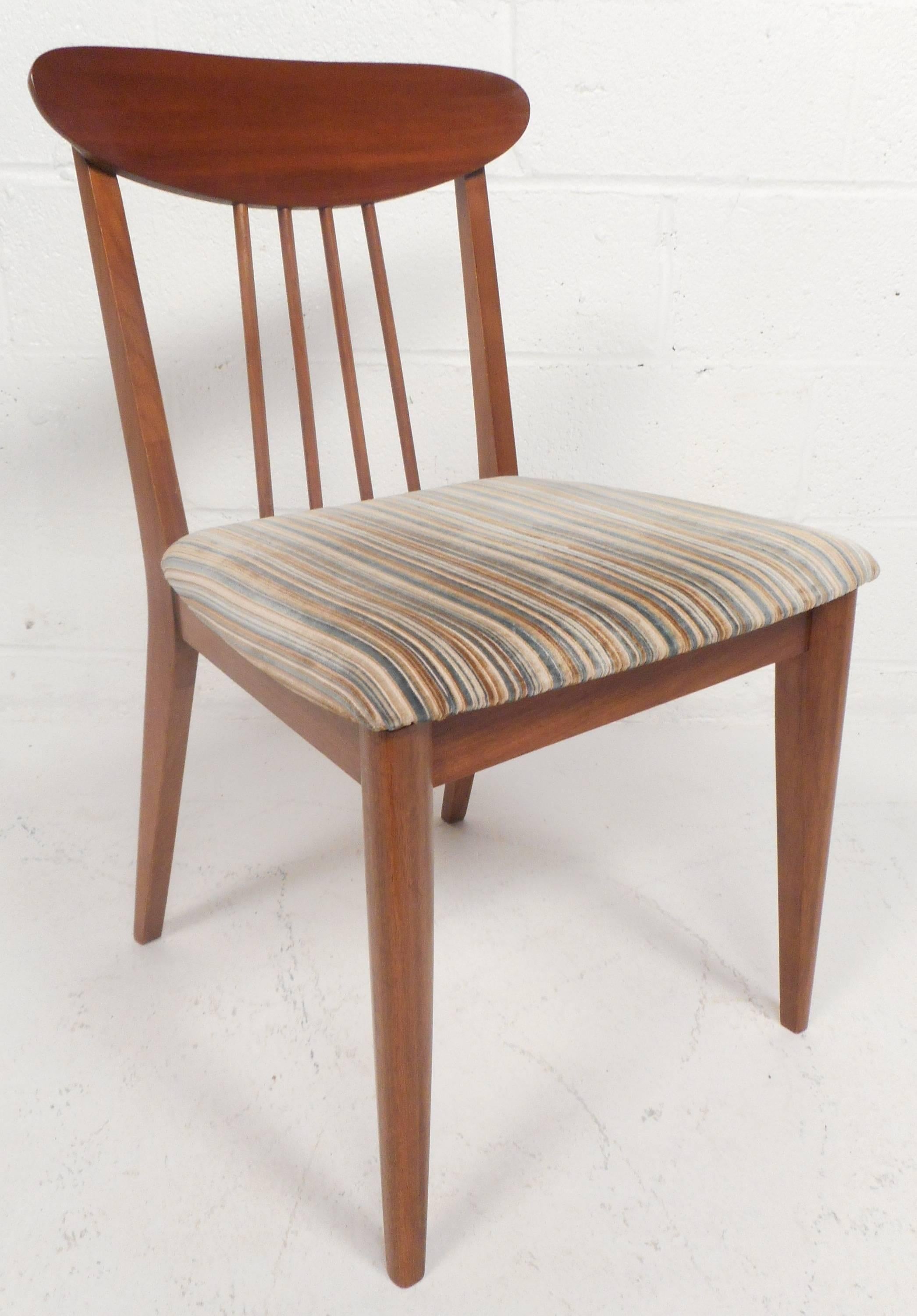 The beautiful set of six dining chairs have colorful plush upholstery and unusual spindle back rests. The vintage walnut finish and tapered legs make this set the perfect addition to any modern interior. Please confirm item location (NY or NJ). 