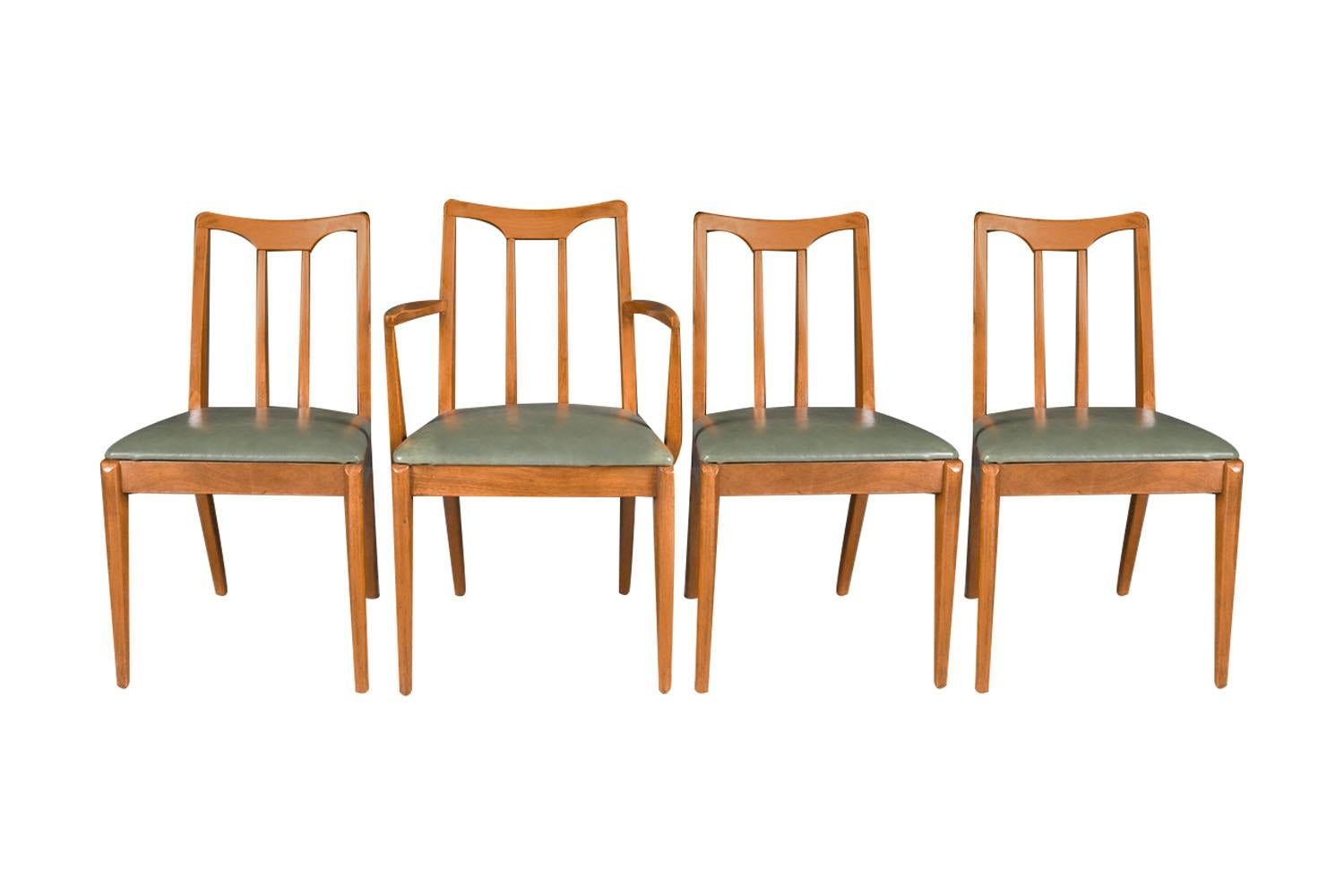 A set of four extremely sought after, gorgeous 1960s, modern walnut side/dining chairs designed by John Van Koert for the Drexel Projection line. Featuring a full matching set of four, one of which has arms, each remains in original condition