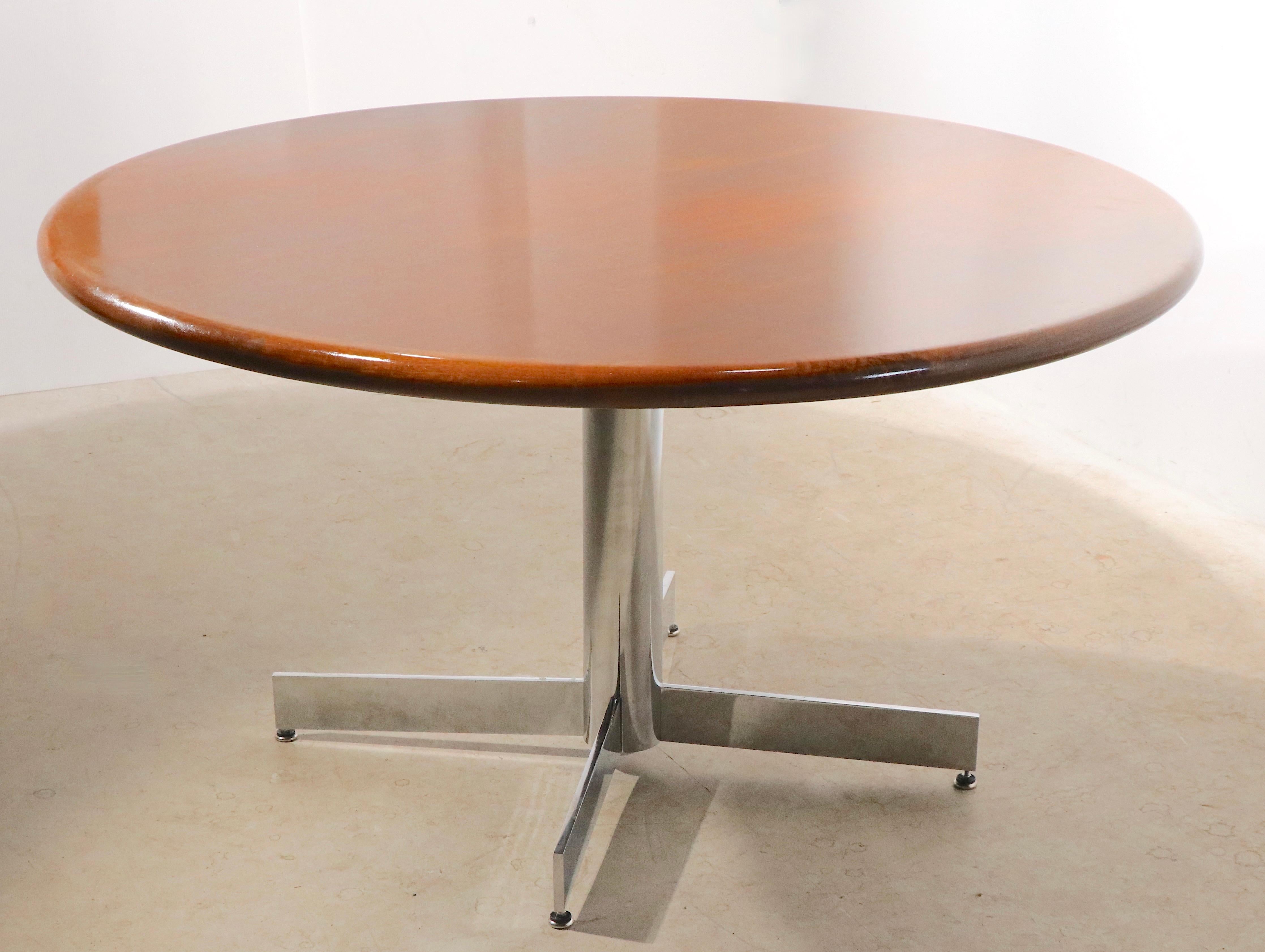 Exceptional dining, or conference table, having a thick solid walnut top, which is supported by a bright chrome pedestal base with four chrome legs which radiate from the center pole. The table comes with a custom cut glass top, included if you want