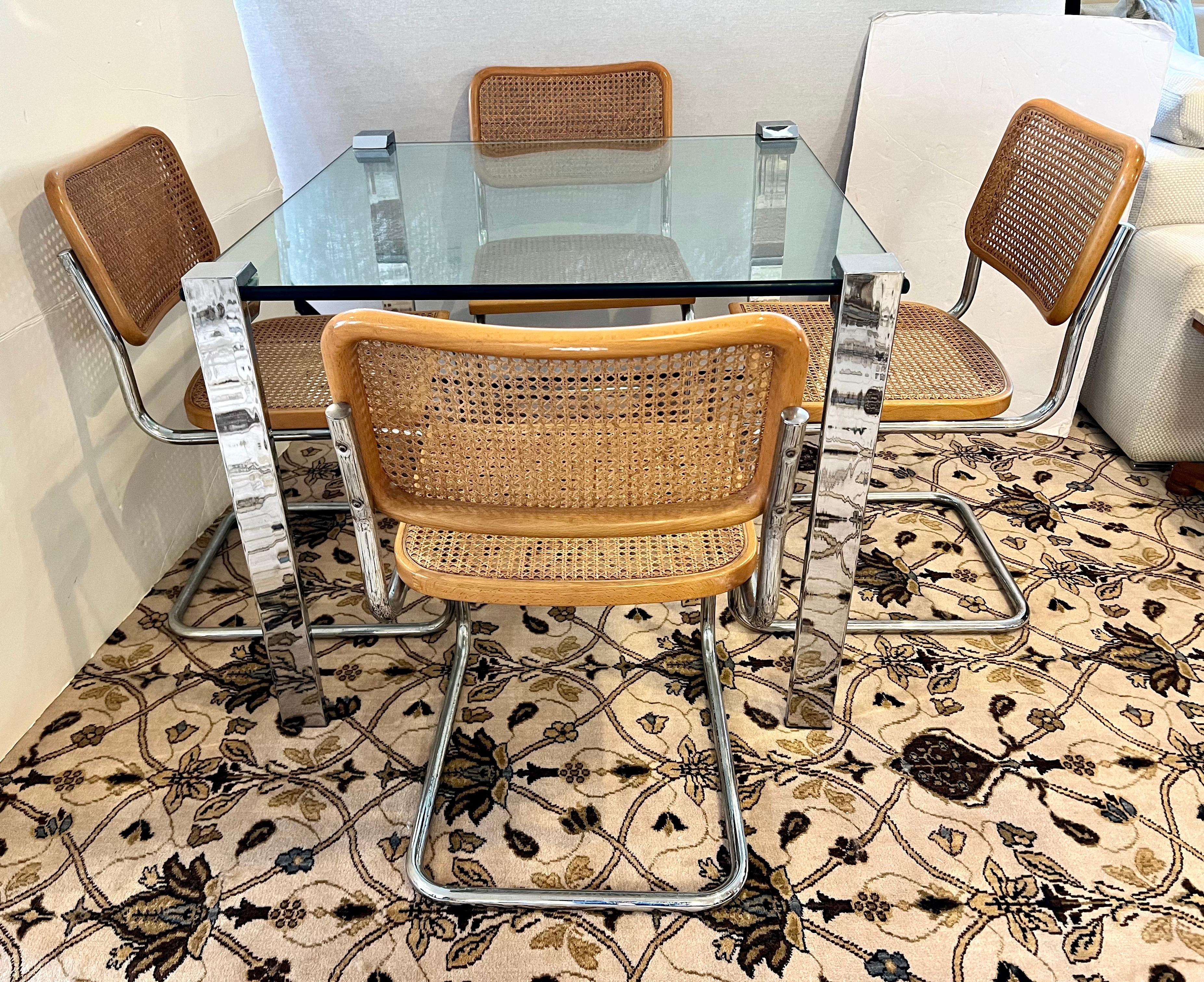 Mid century small dining set includes a chrome and glass square table with four Marcel Breuer Cesca cane and chrome tubular chairs, made in Italy. Can also be used as a game table set. Legs screw off for ease of movement.
Measures: Glass