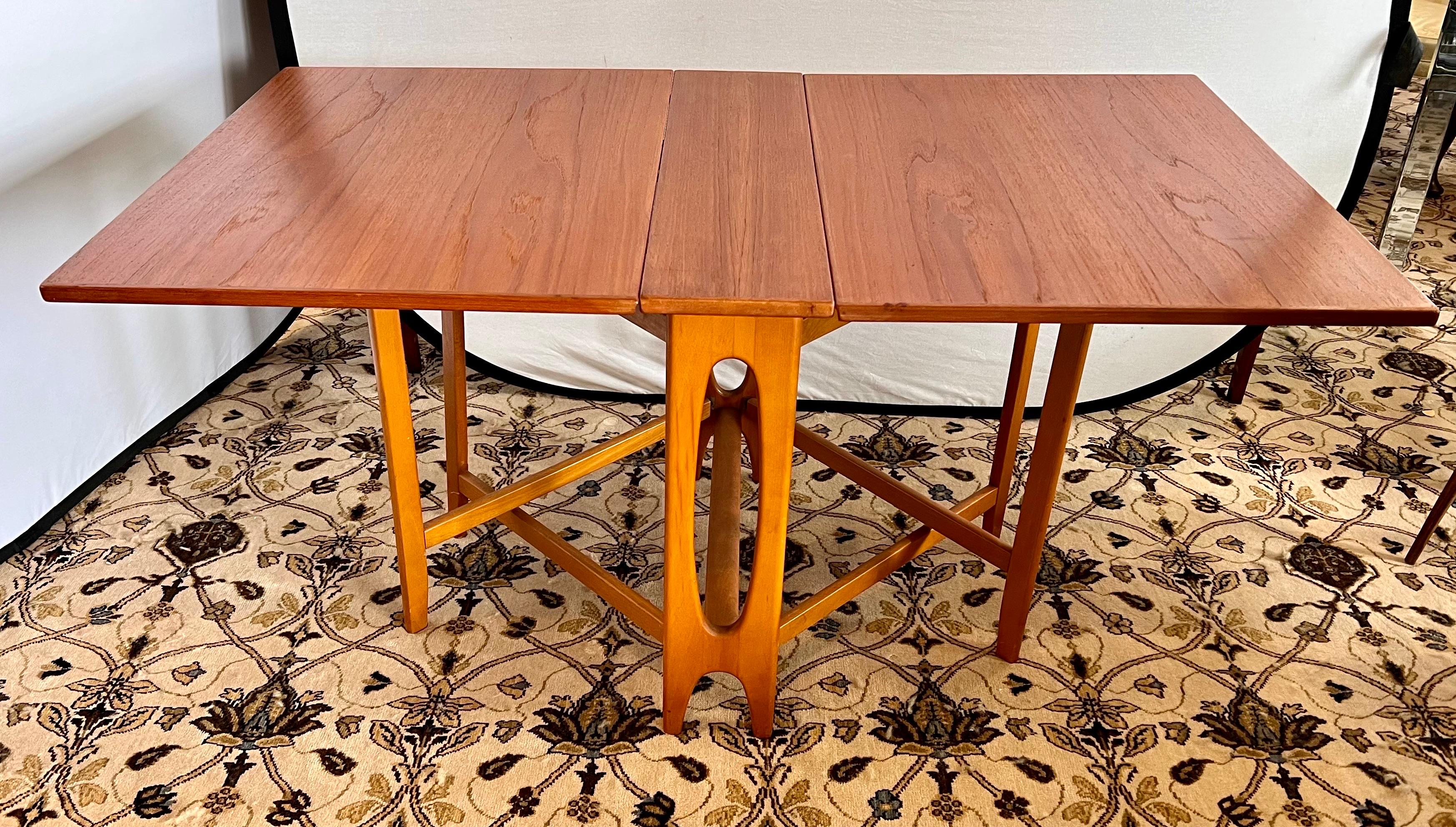 Rare Danish modern dual gate-leg teak table that is surrounded by natural walnut Norman Cherner side chairs, a set of six. Danish Modern (table) meets Mid Century Modern (chairs) and the marriage looks like a compelling one!  Why not own the best?